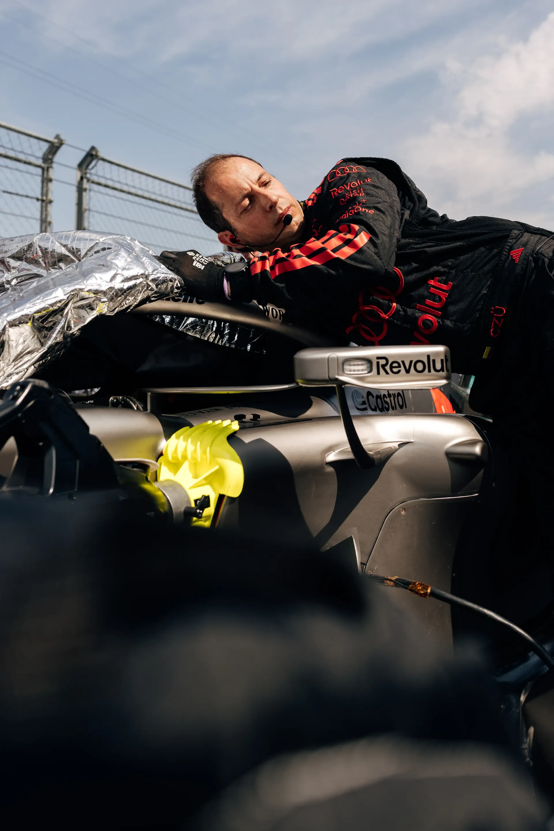 An Audi Revolut F1® Team mechanic leans over the Audi R26 while working on the car in the garage.