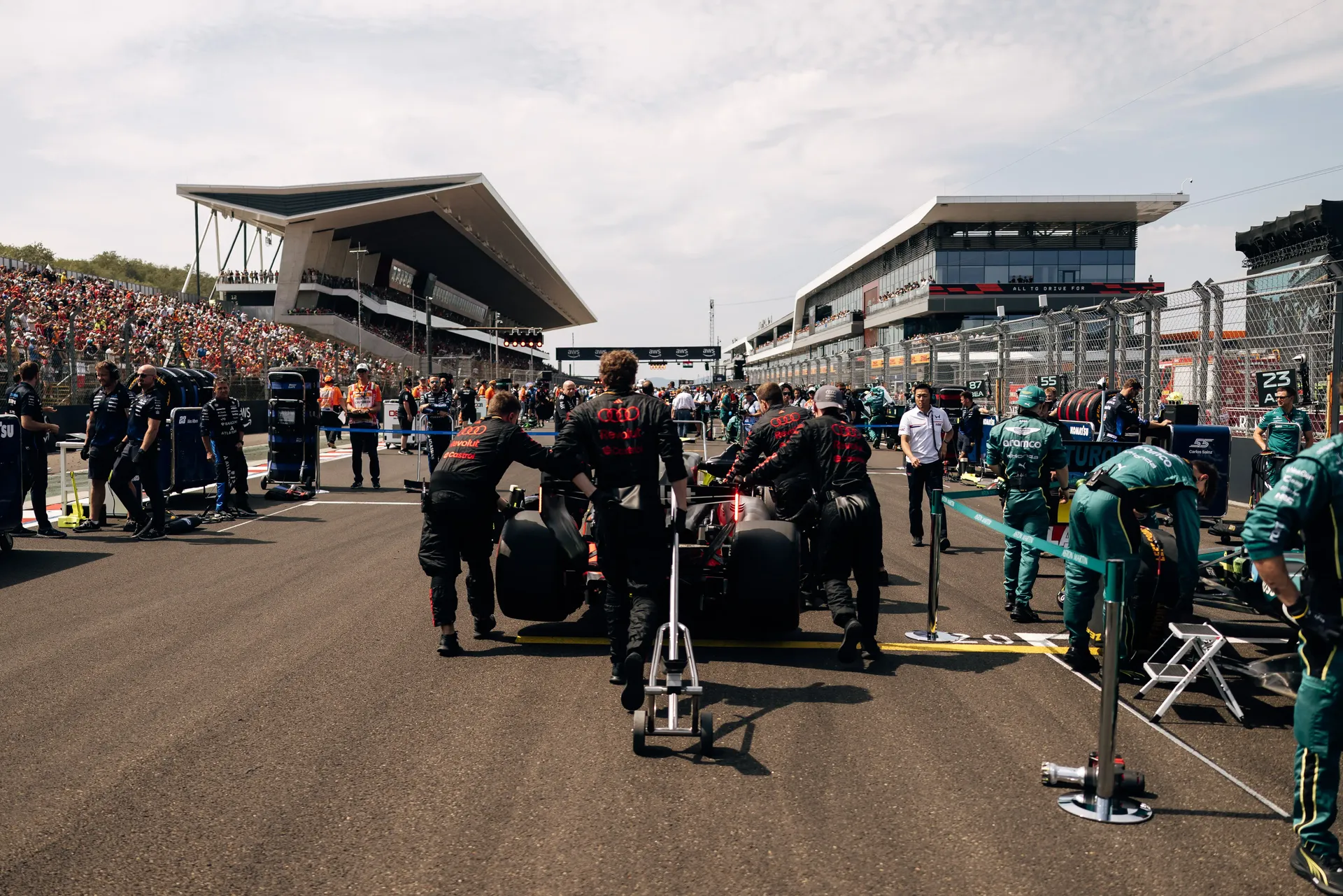The Audi Revolut F1® Team Audi R26 is surrounded by team personnel on the Hungaroring starting grid ahead of the Hungarian Grand Prix.