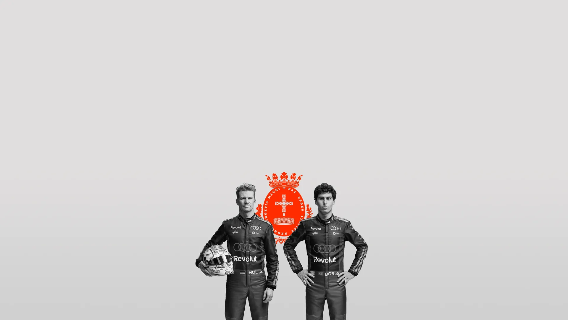 Black and white front shot of Audi Revolut F1® Team driver Nico Hulkenberg and Gabriel Bortoleto posing in front of the Monza sigil in the studio
