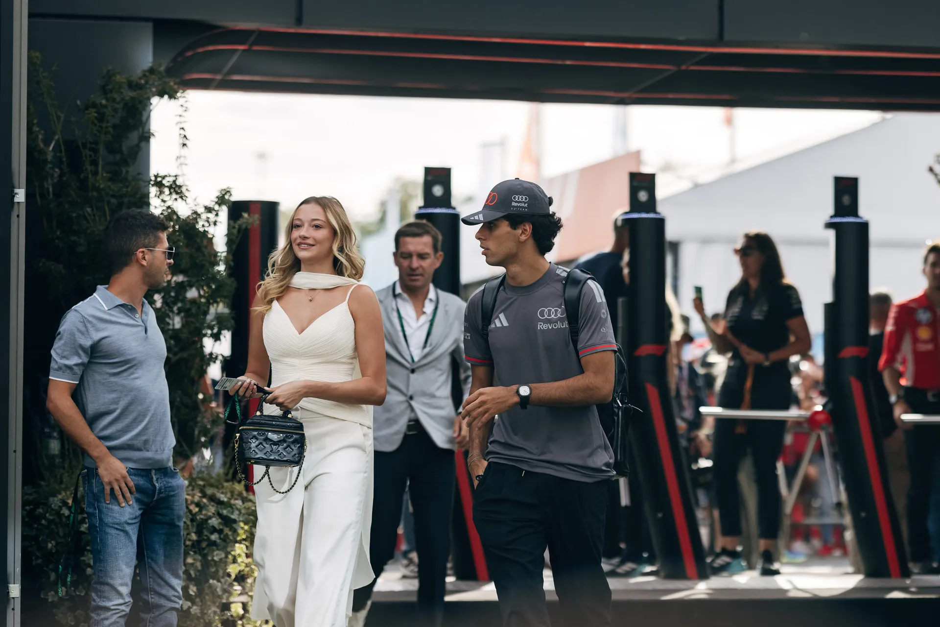 Audi Revolut F1® Team driver Gabriel Bortoleto arriving in the paddock, chatting with Nico Hulkenberg and team members.