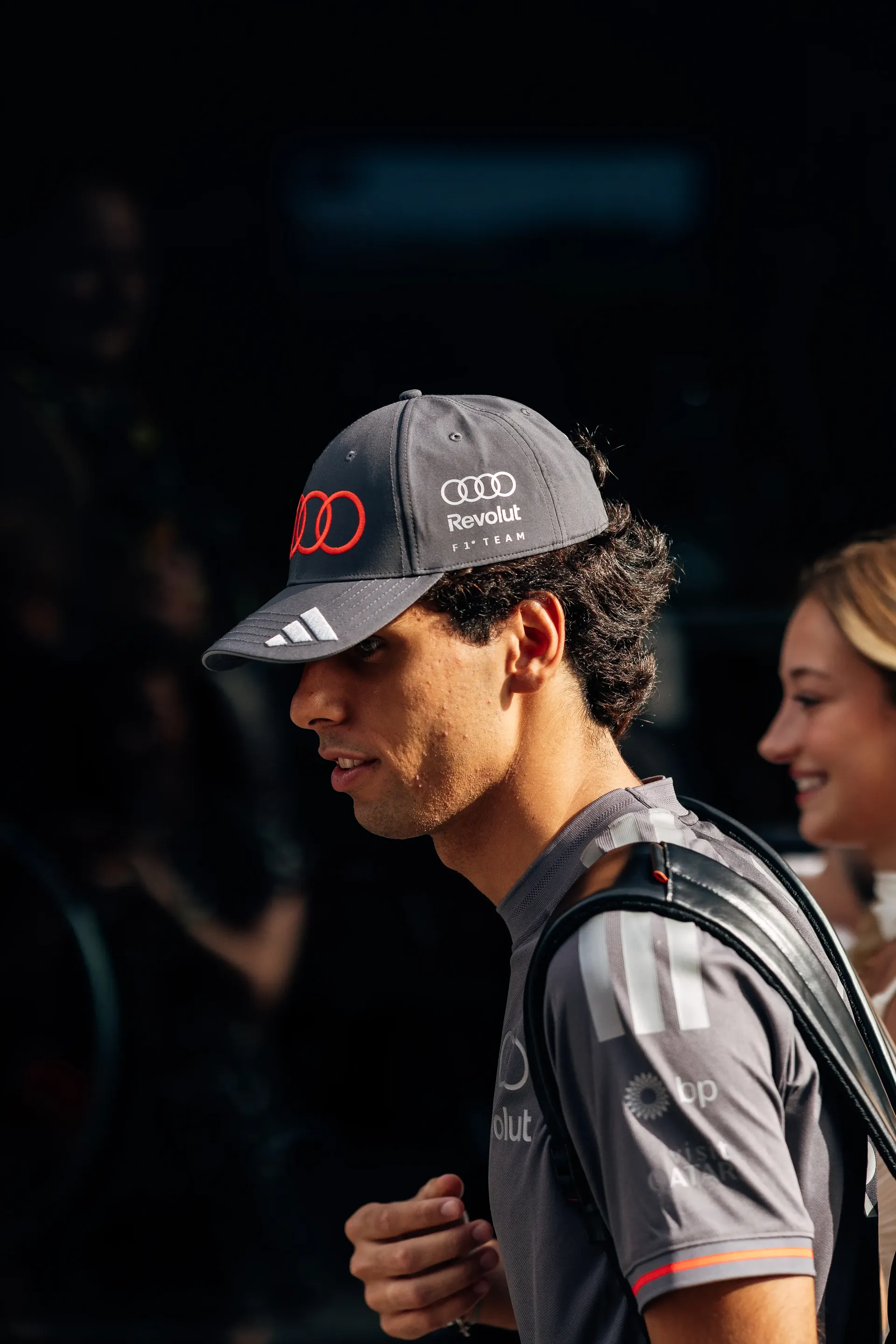Side-profile portrait of Audi Revolut F1® Team driver Gabriel Bortoleto wearing an Audi Revolut F1 Team cap and backpack.