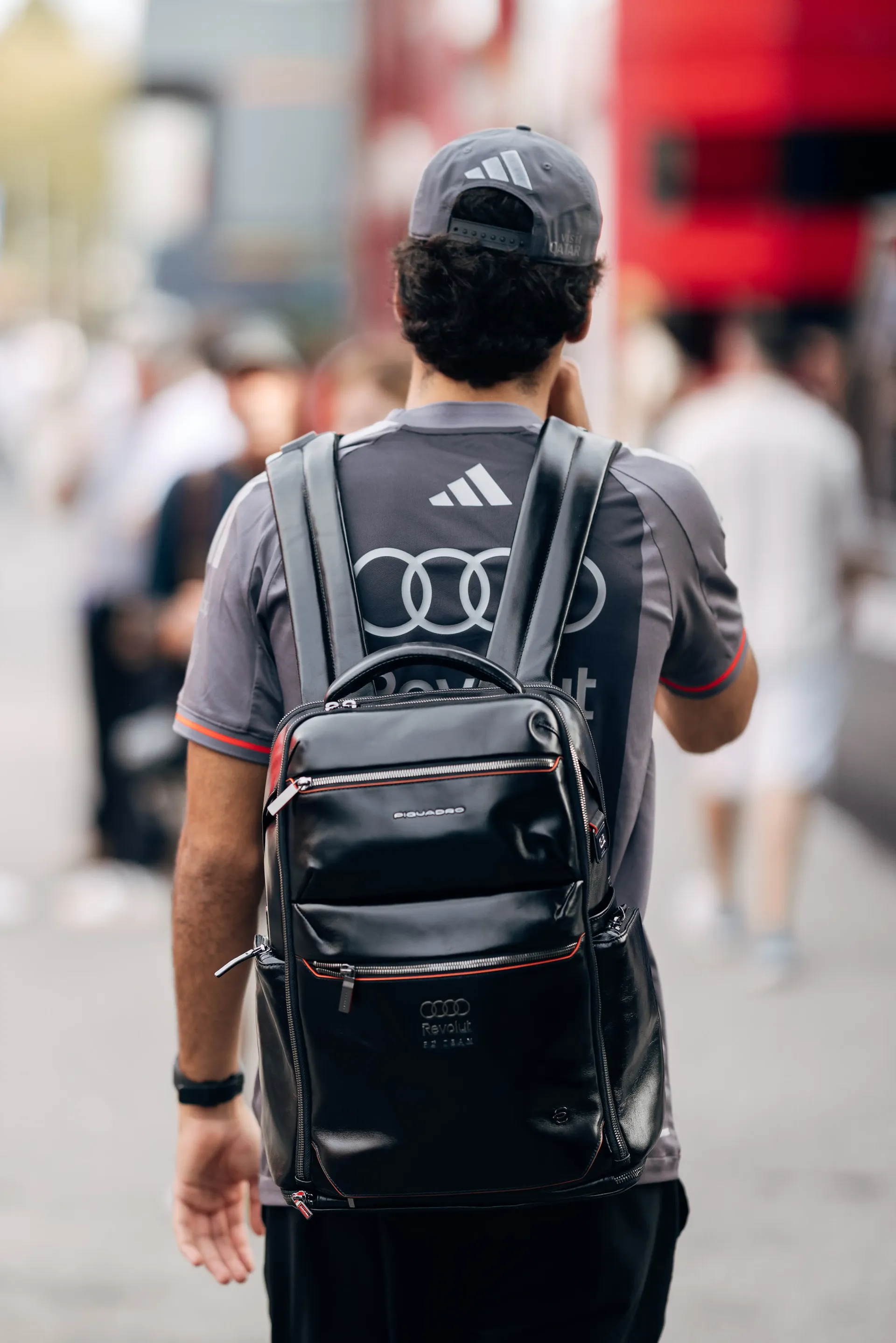Rear view of Audi Revolut F1® Team driver Gabriel Bortoleto walking through the Monza paddock with a backpack.