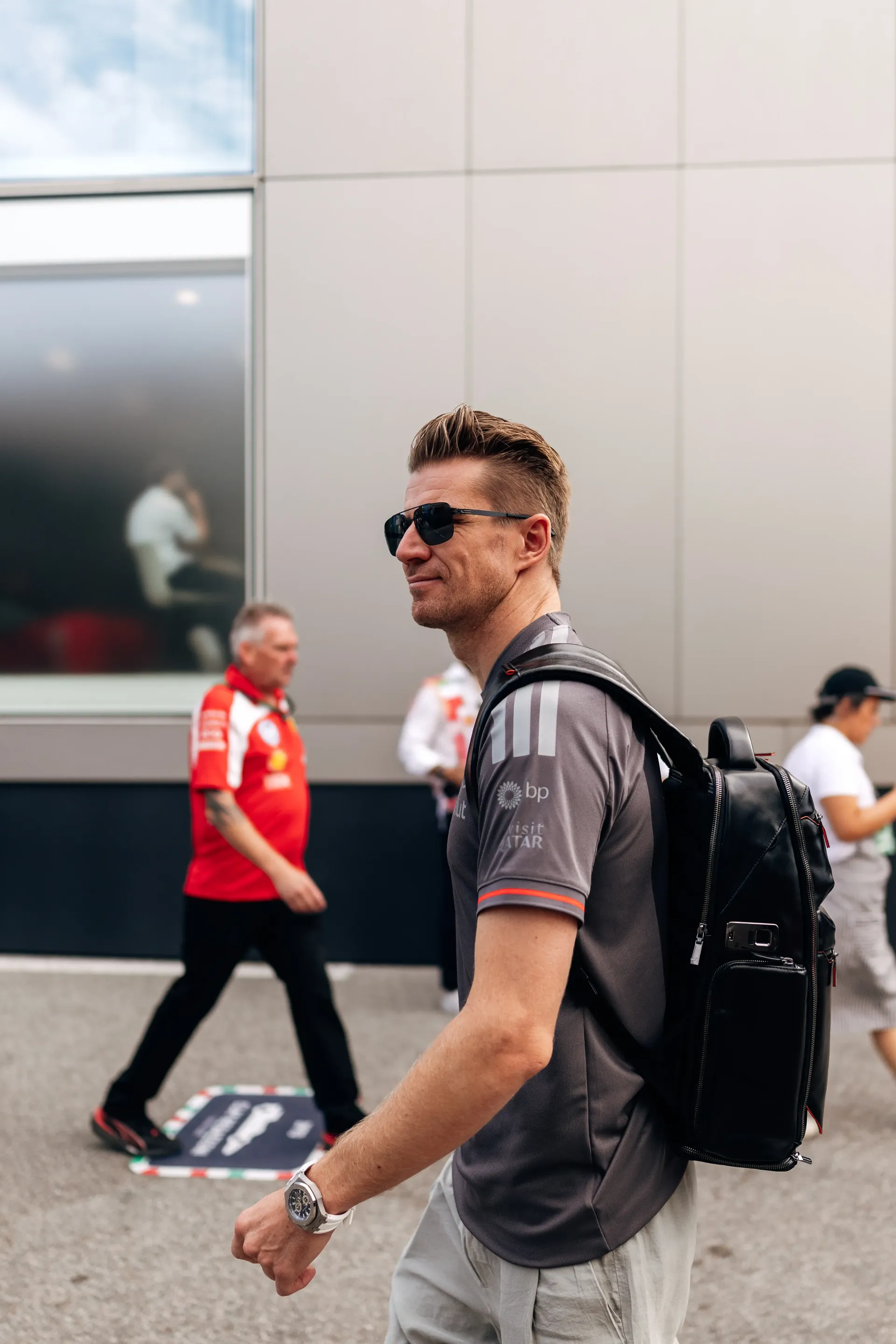 Audi Revolut F1® Team driver Nico Hulkenberg looking back over his shoulder while walking past the Audi Revolut F1 Team hospitality building.