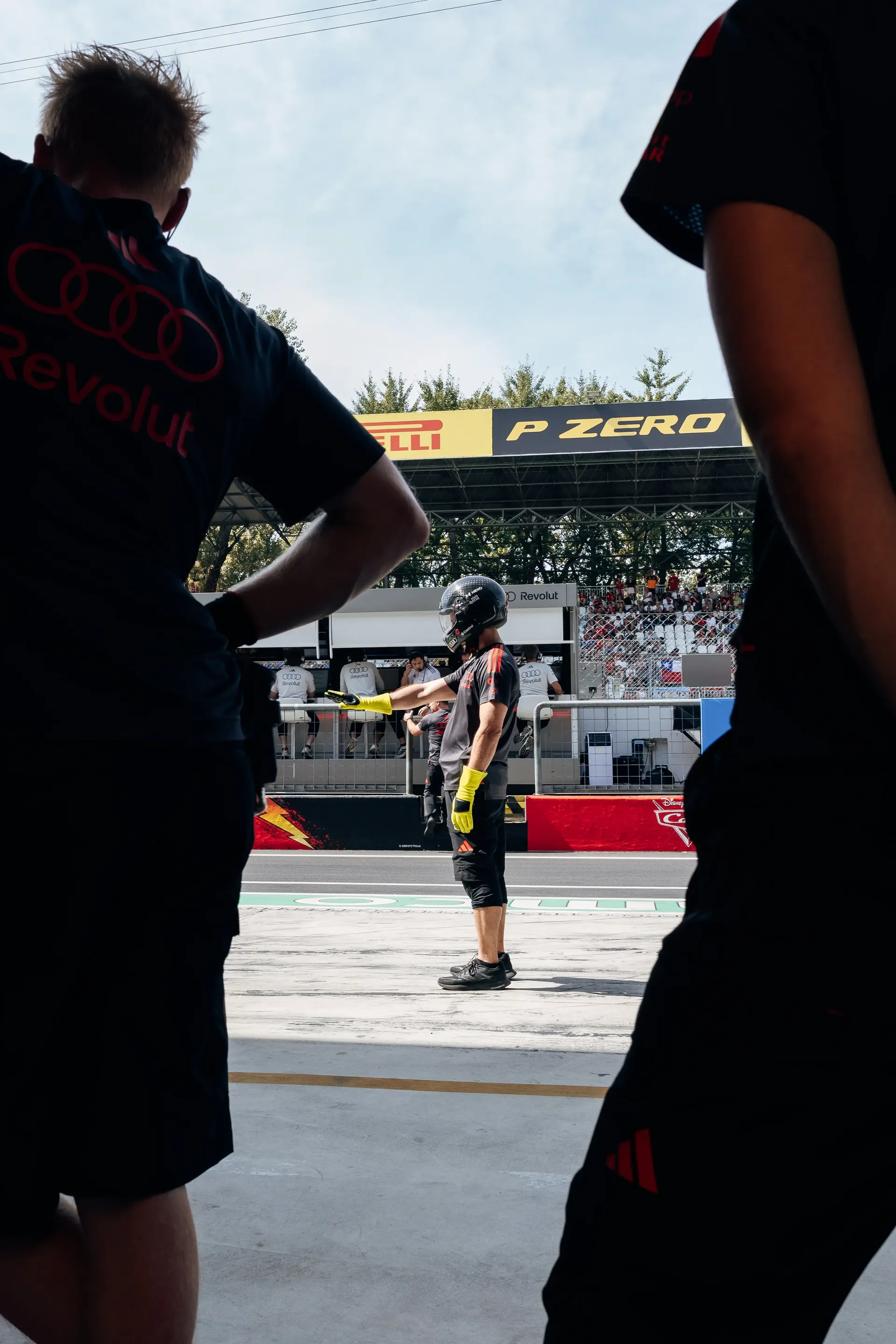 Audi Revolut F1® Team personnel standing at the garage entrance overlooking the pit lane.
