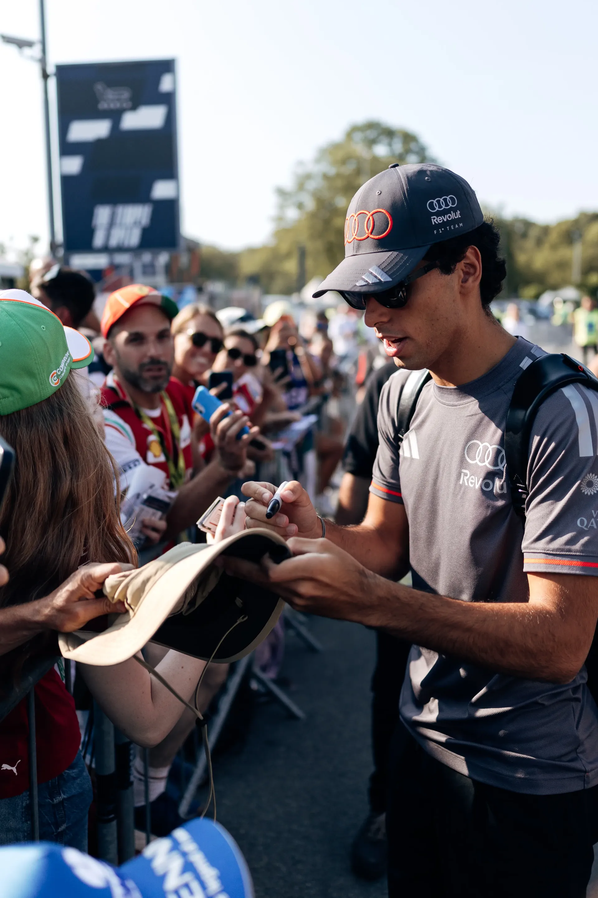 Gabriel Bortoleto, driver of the Audi Revolut F1® Team, signs autographs for fans during arrival at the 2026 Italian Grand Prix paddock.