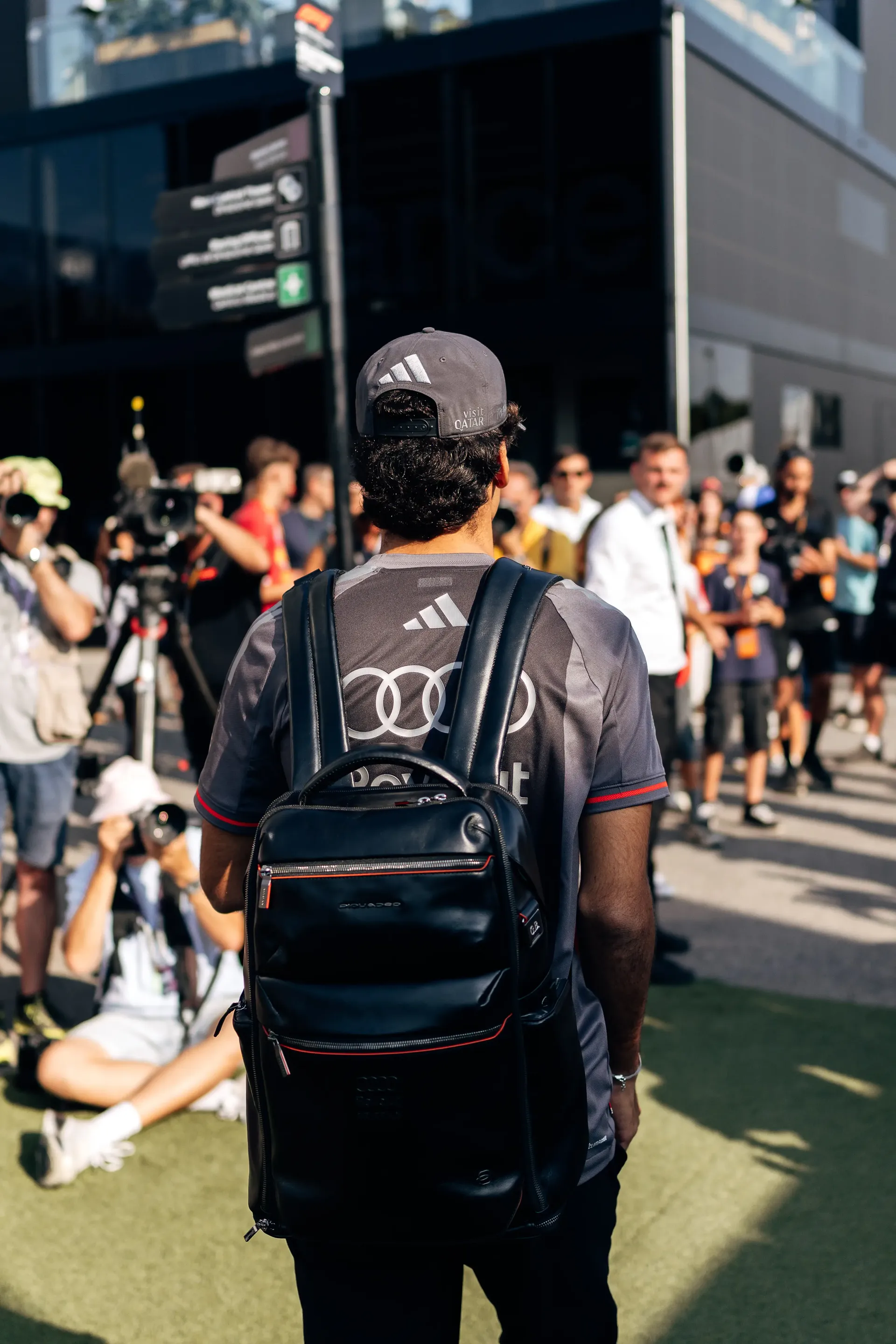 Rear view of Gabriel Bortoleto, driver of the Audi Revolut F1® Team, entering the Italian Grand Prix paddock with fans lining the walkway.