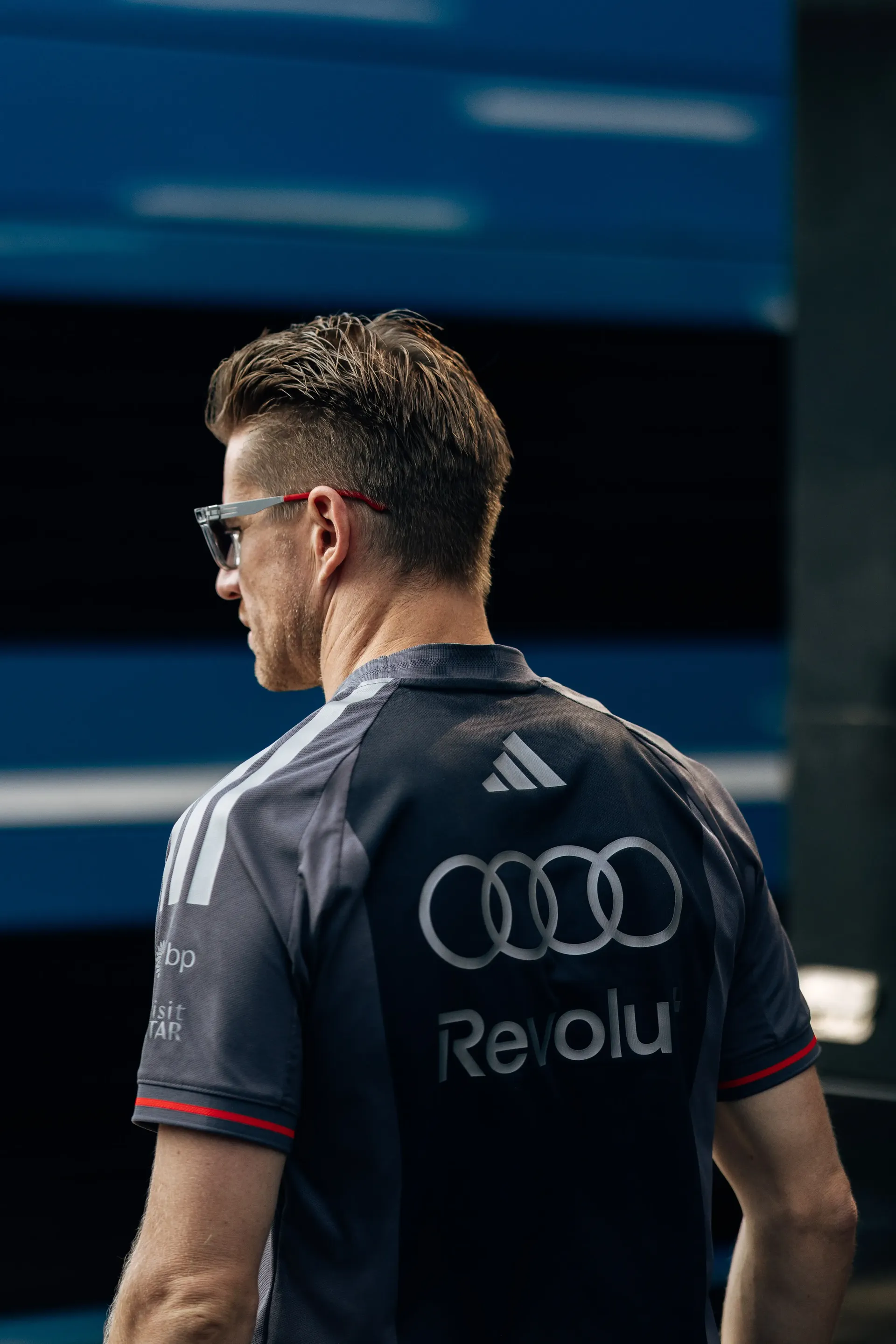 Rear portrait of Gabriel Bortoleto, driver of the Audi Revolut F1® Team, wearing team kit while walking through the Monza paddock.