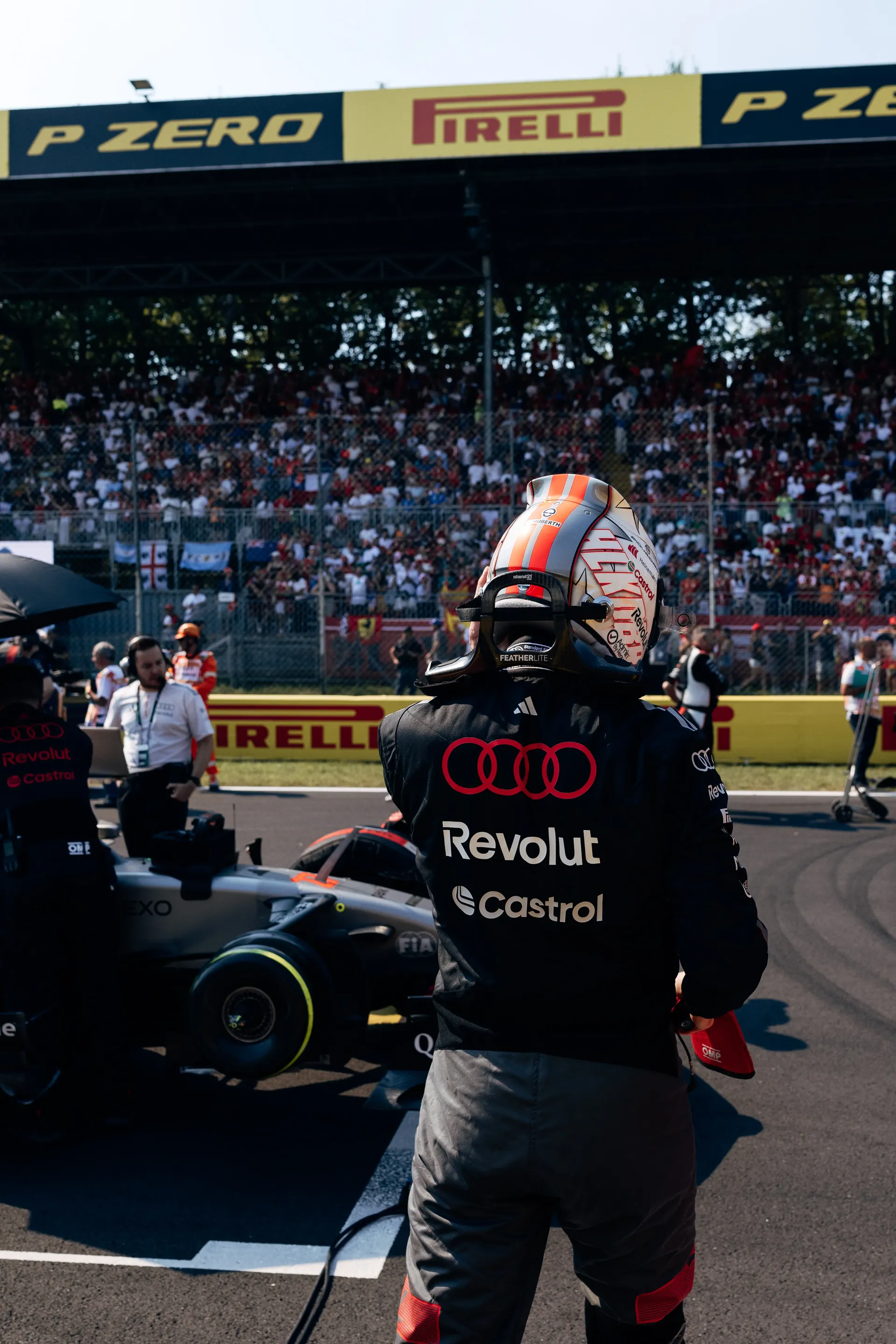 Audi Revolut F1® Team mechanic and driver Nico Hulkenberg standing beside the Audi R26 in the pit lane