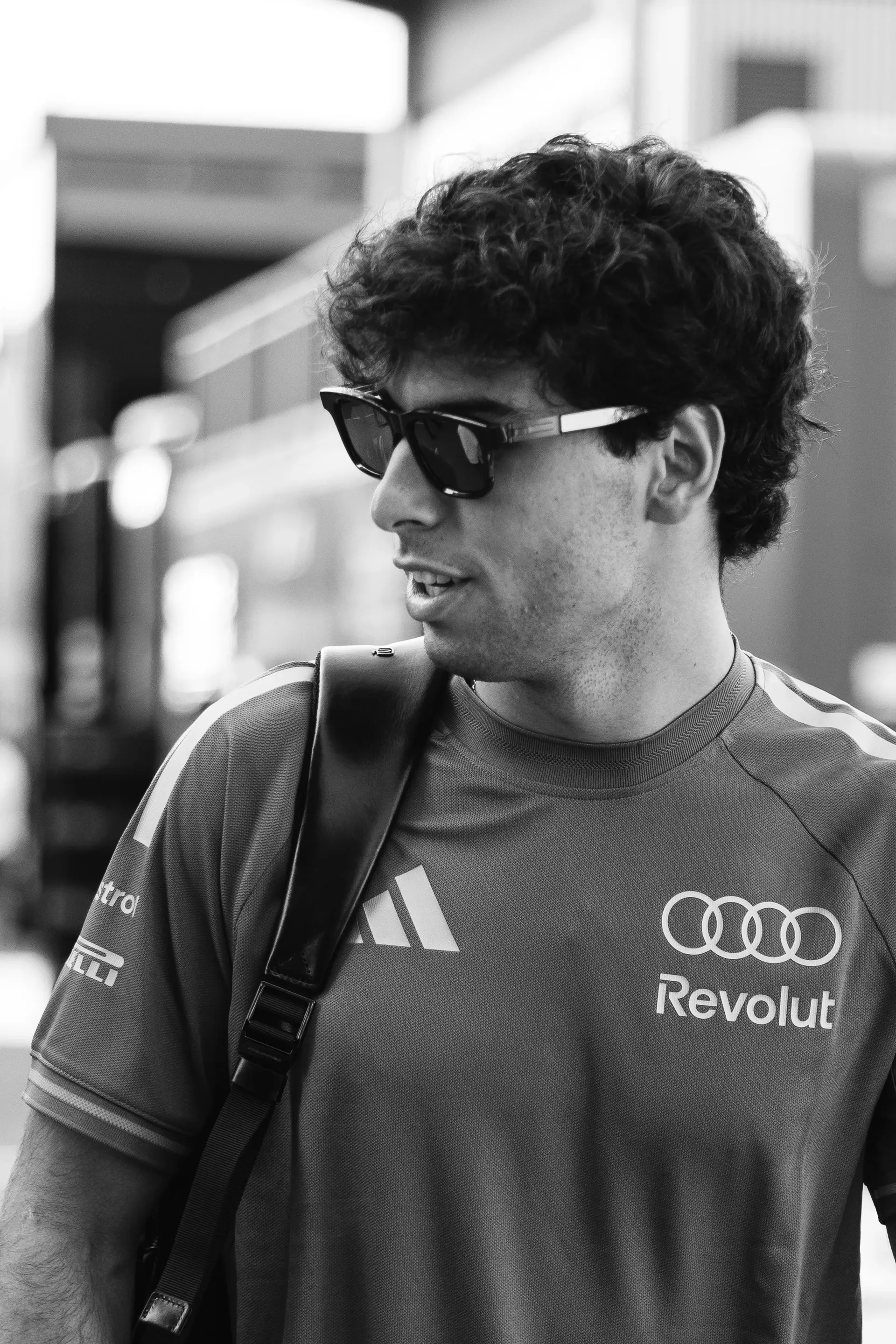 Black and white shot of Audi Revolut F1® Team driver Gabriel Bortoleto during Thursday arrivals at the Italian Grand Prix wearing sunglasses.