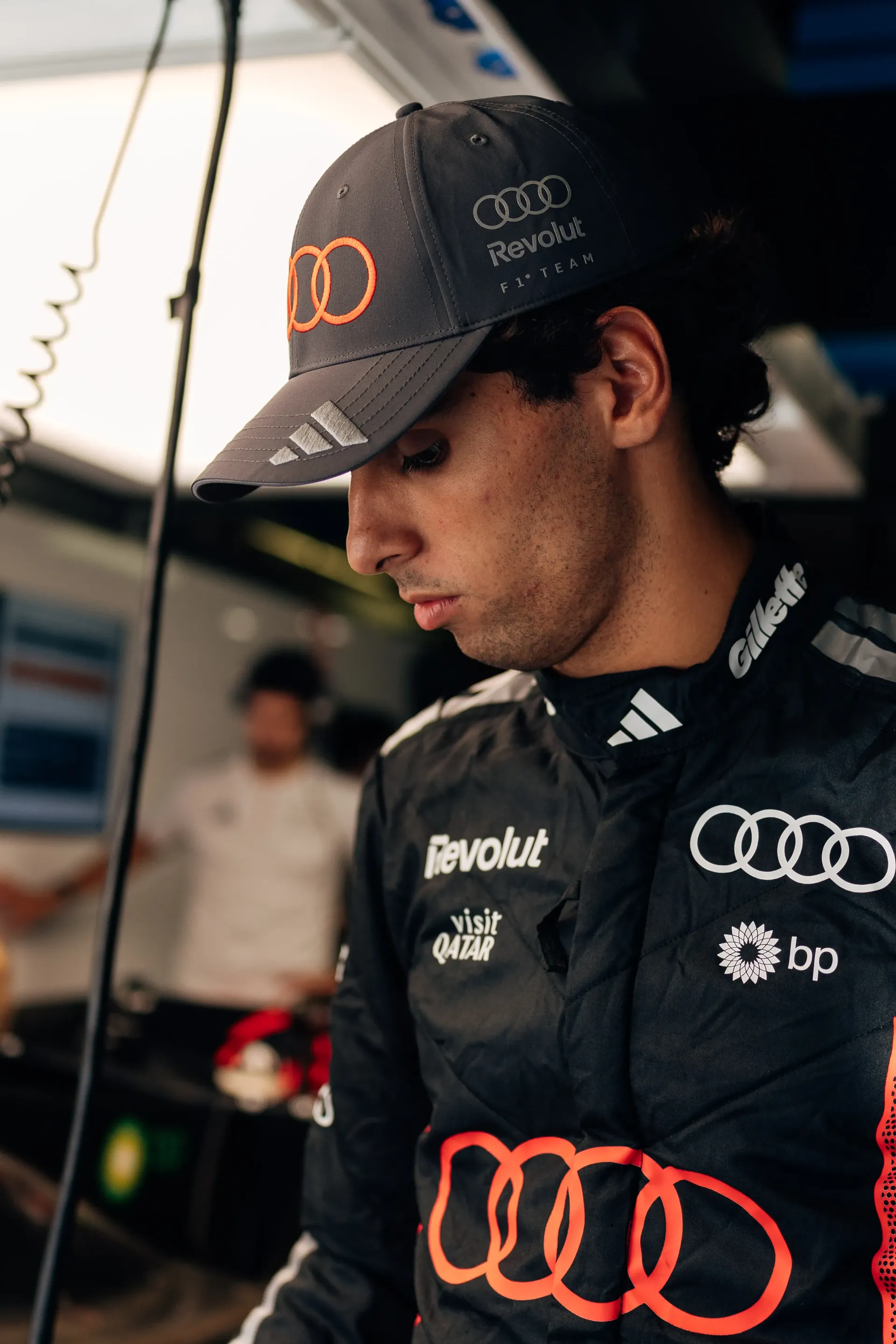 Close-up of Gabriel Bortoleto in his Audi Revolut F1® Team race suit and cap inside the garage.