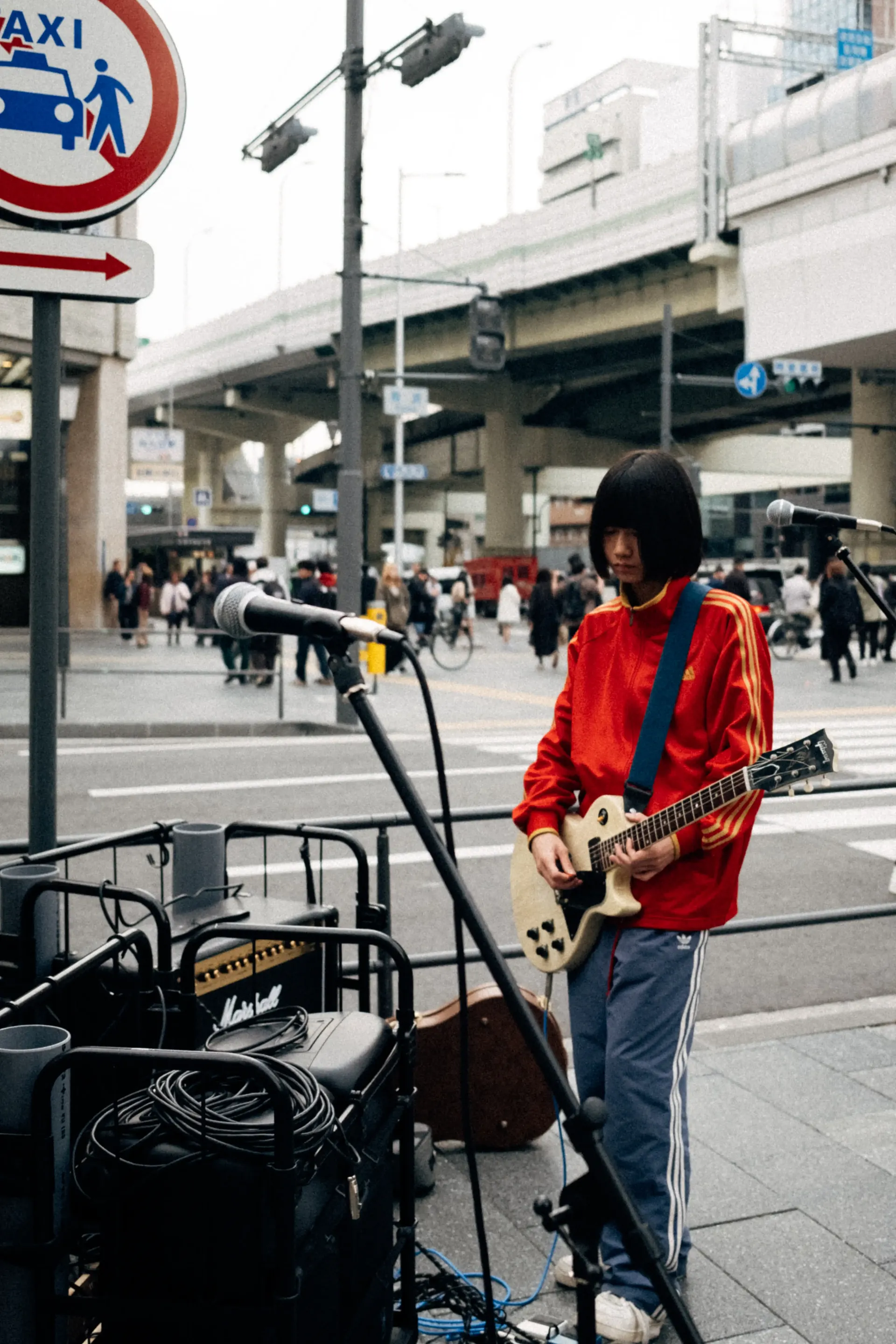 Street musician playing guitar in a busy Japanese city street, urban culture around Suzuka during Japanese Grand Prix.