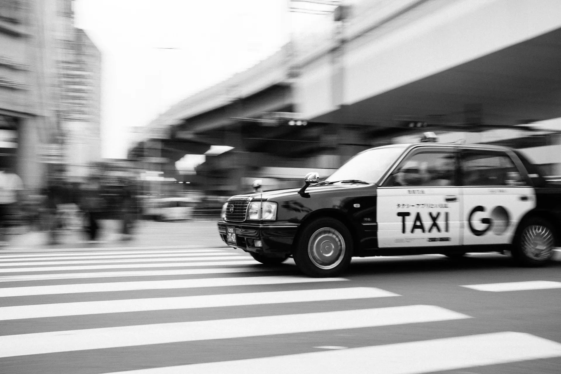 Japanese taxi driving across a crosswalk in a city near Suzuka Circuit, everyday life during Grand Prix weekend.