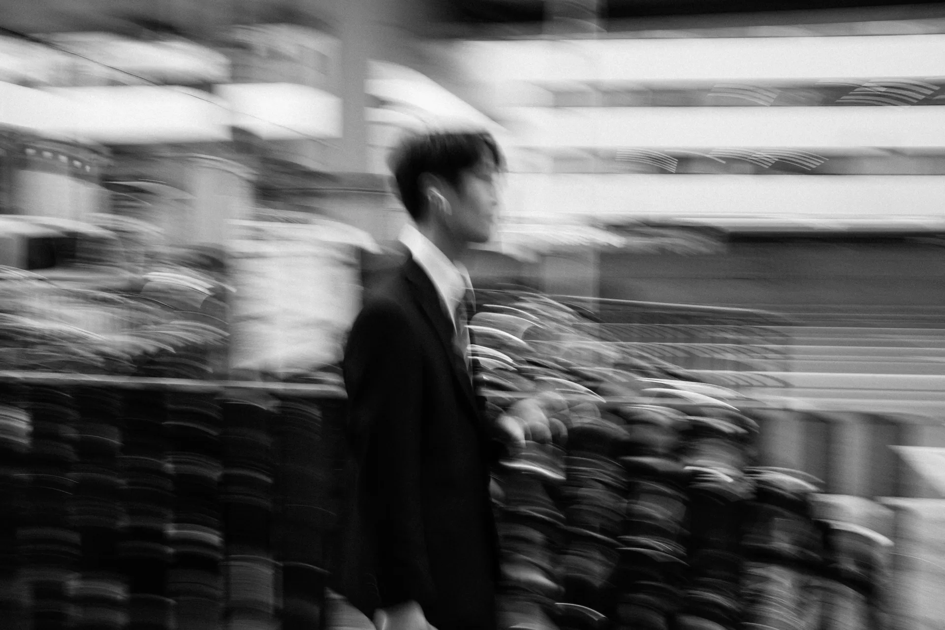 Motion-blurred businessman walking past parked bicycles in Japan, fast-paced city life during the Suzuka Grand Prix.