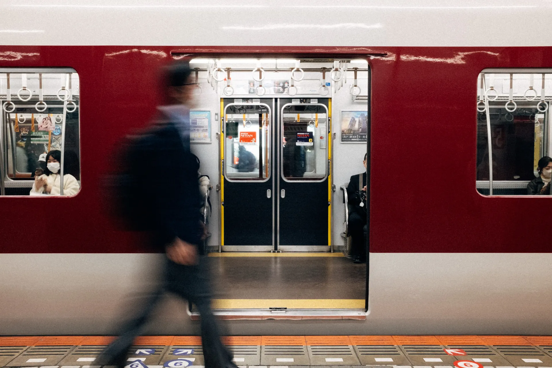 Red commuter train with passengers at a station in Japan, public transport during Japanese Grand Prix weekend.