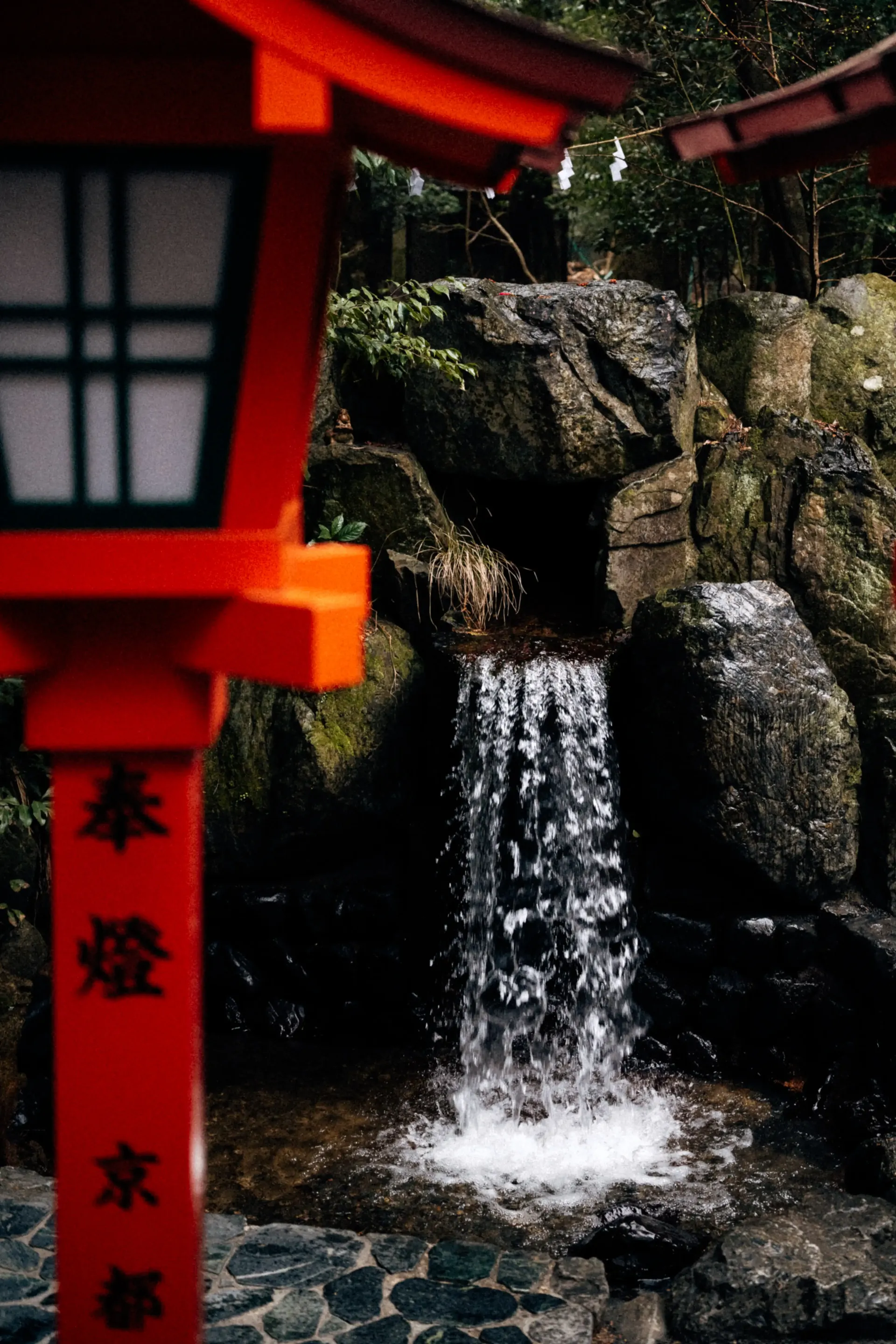 Small waterfall beside a red shrine structure in Suzuka, blending Japanese culture with the Japanese Grand Prix travel experience