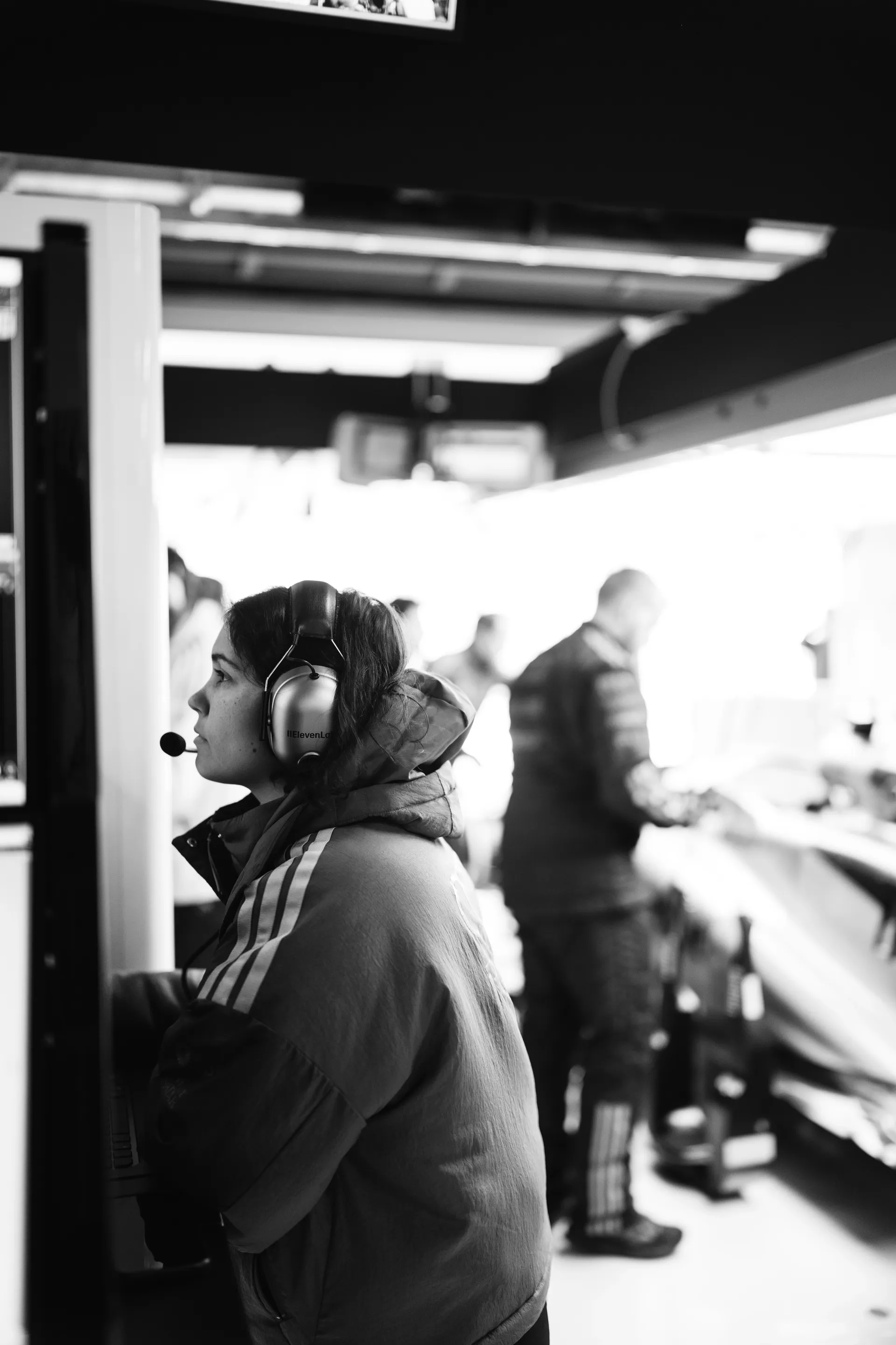 Audi Revolut F1® Team staff member wearing a headset and microphone monitoring activity inside the garage during practice preparations.