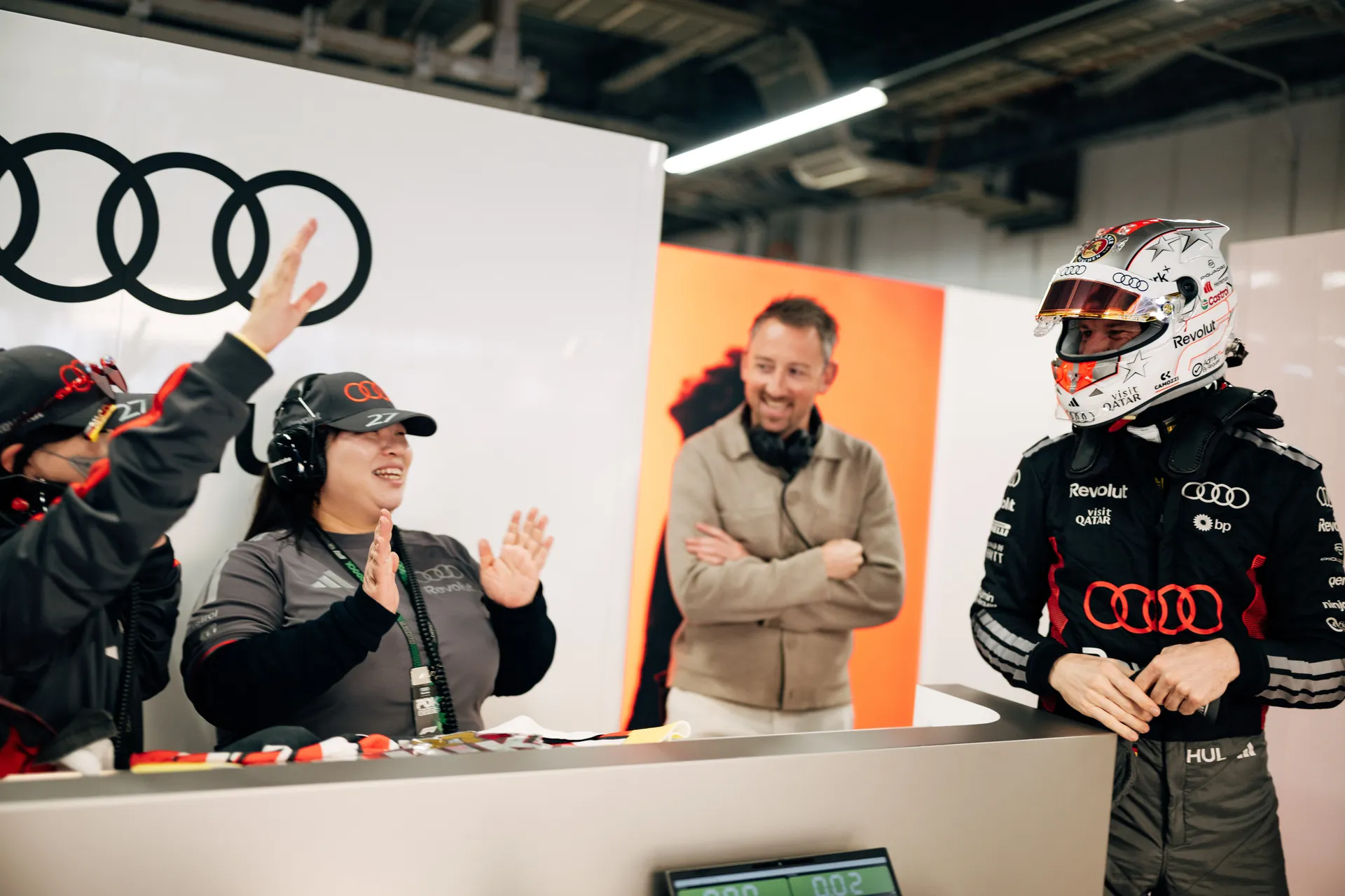 Nico Hulkenberg receiving applause from team members at the Audi Revolut F1® Team garage desk.