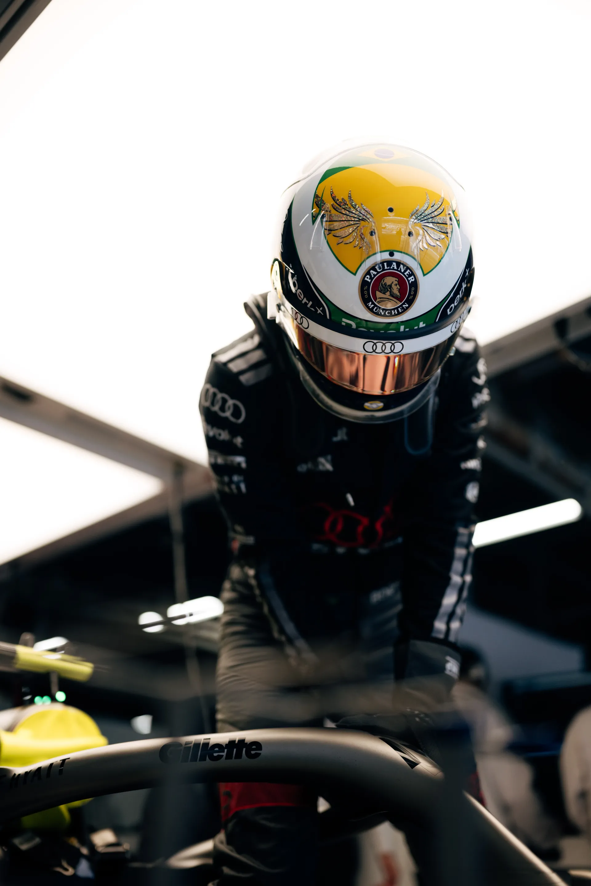 Gabriel Bortoleto Audi Revolut F1® Team driver leaning over the cockpit of the car under bright garage lights.