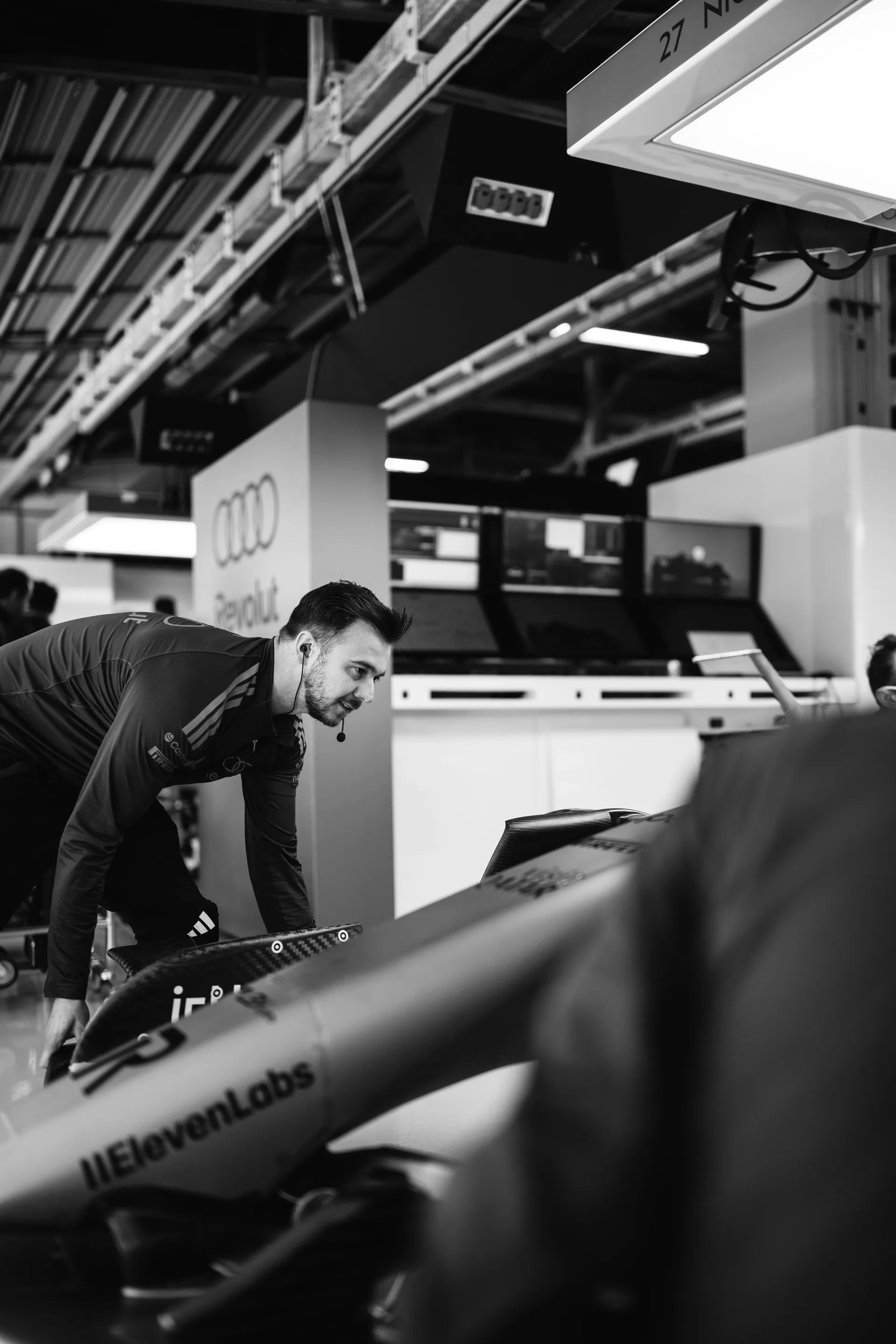 Team member leaning over an Audi Revolut F1® Team car inside the Suzuka garage, with the Audi branding and garage workstation visible in the background.