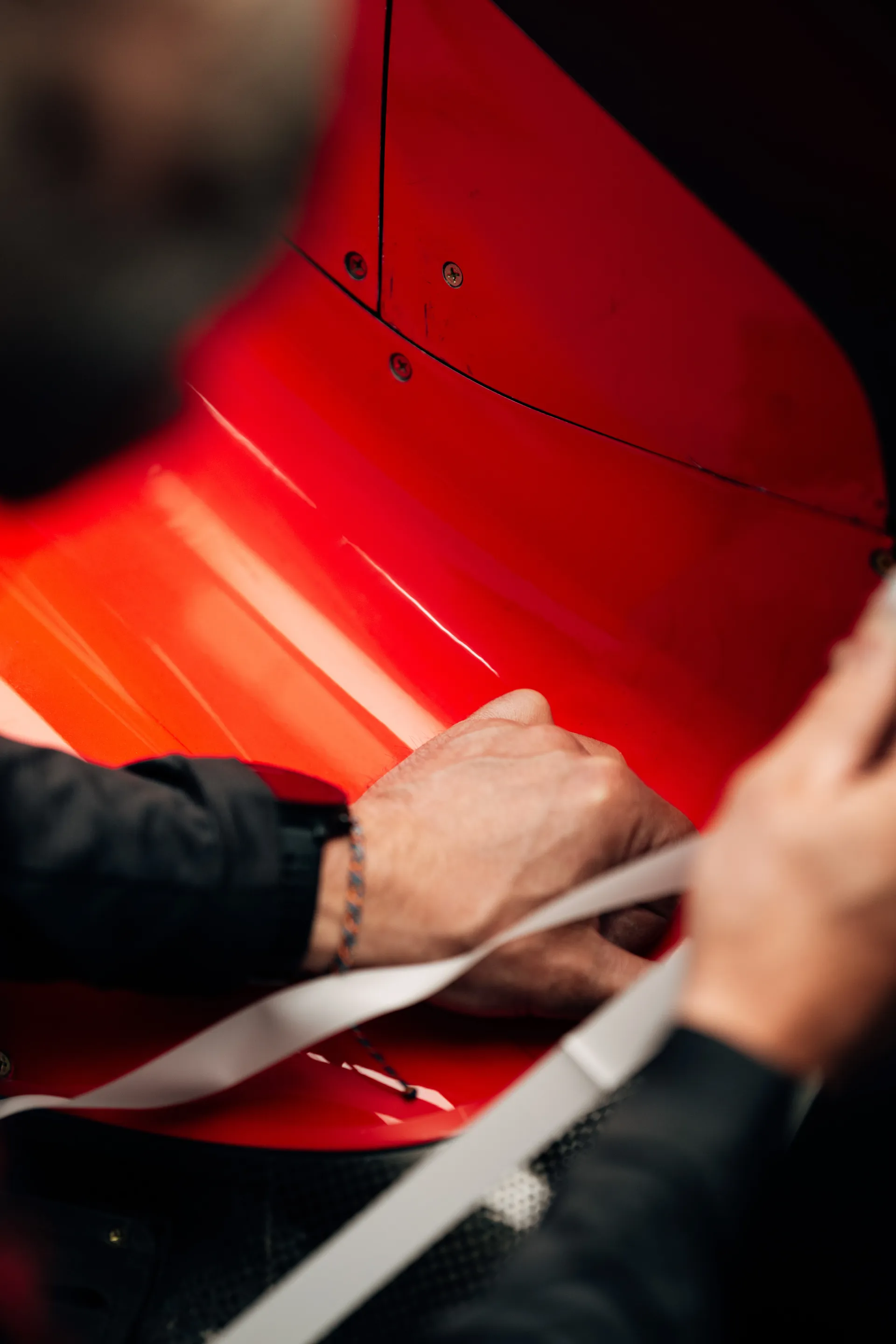 Close up of team members’ hands applying tape or measuring material along the red bodywork of the Audi Revolut F1® Team car.