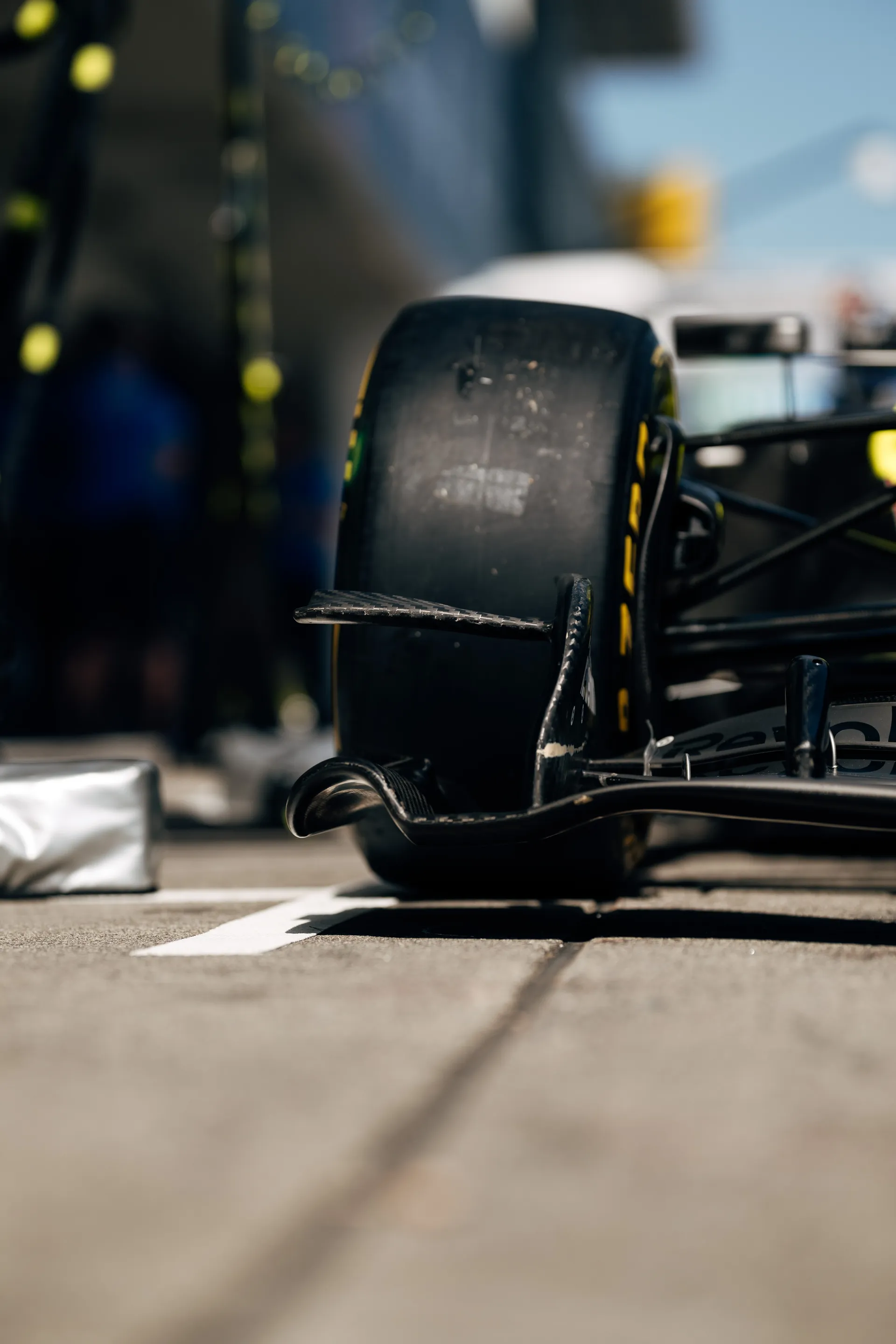 Low angle close up of the front tire and front wing elements of the Audi Revolut F1® Team car positioned on the pit lane markings.