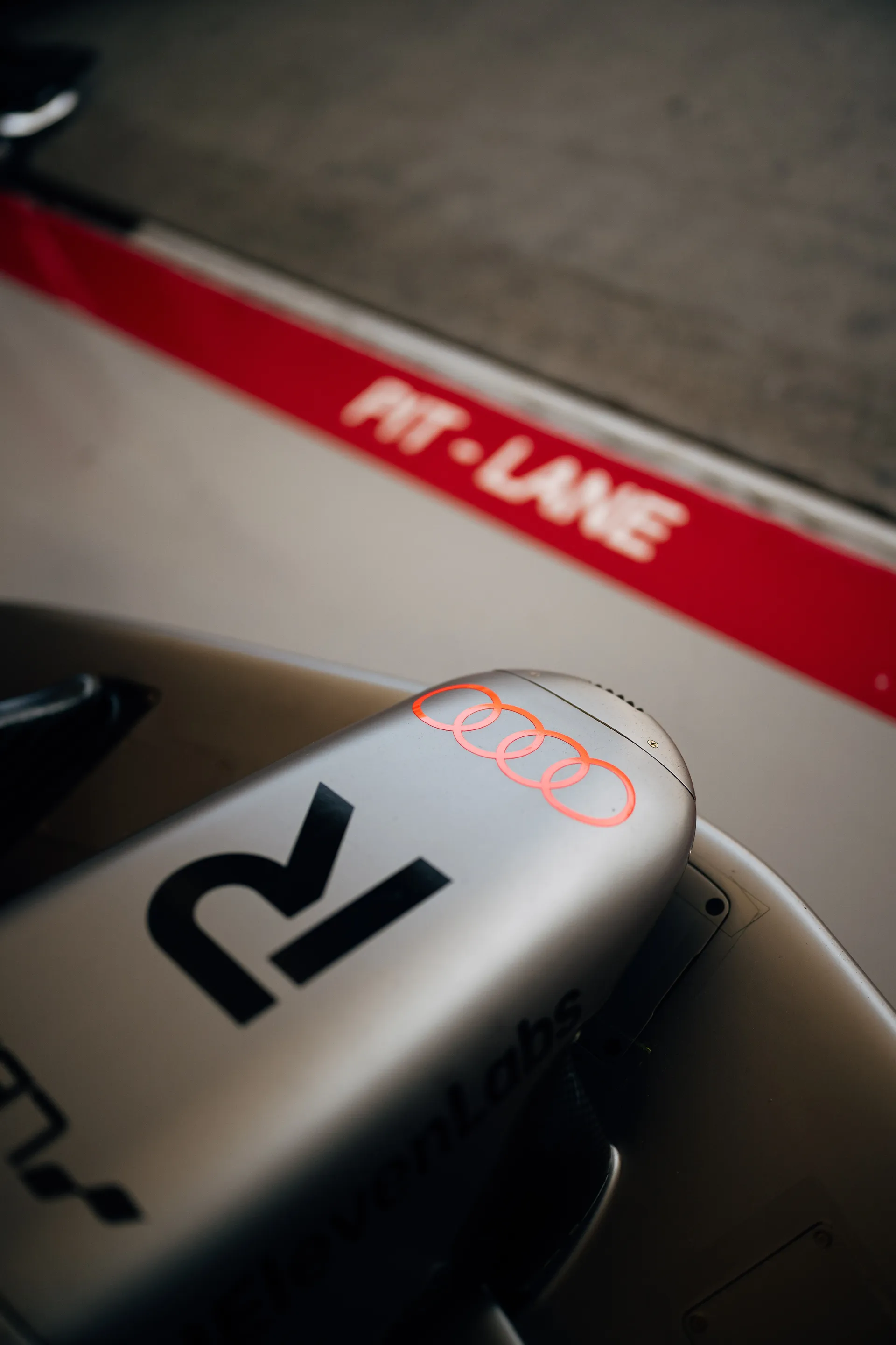 Close up of the rear section of the Audi Revolut F1® Team car near the pit lane line, with the red “PIT LANE” marking blurred in the background.