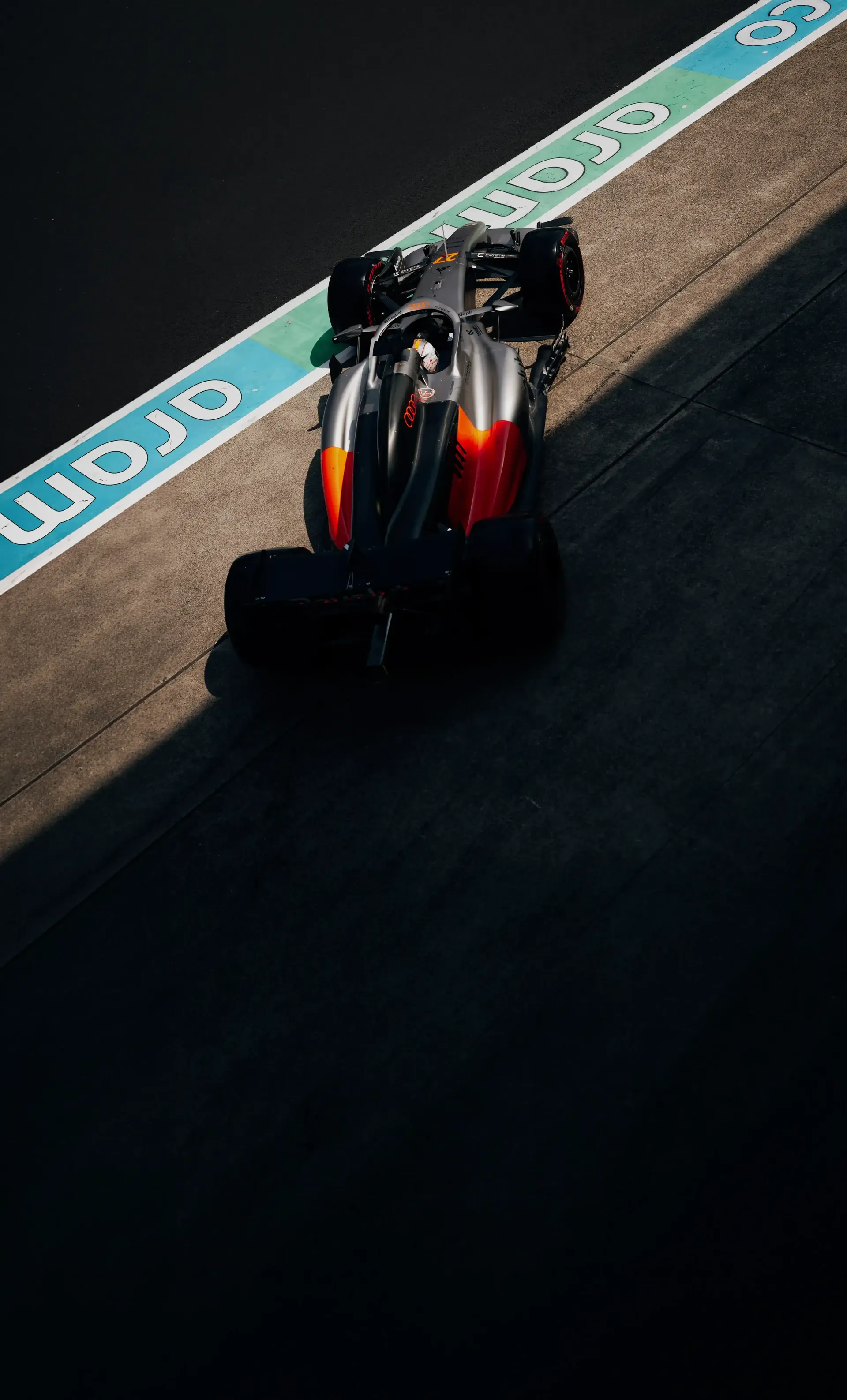 High angle shot of an Audi Revolut F1® Team car running along the Suzuka pit lane near the turquoise lane markings.