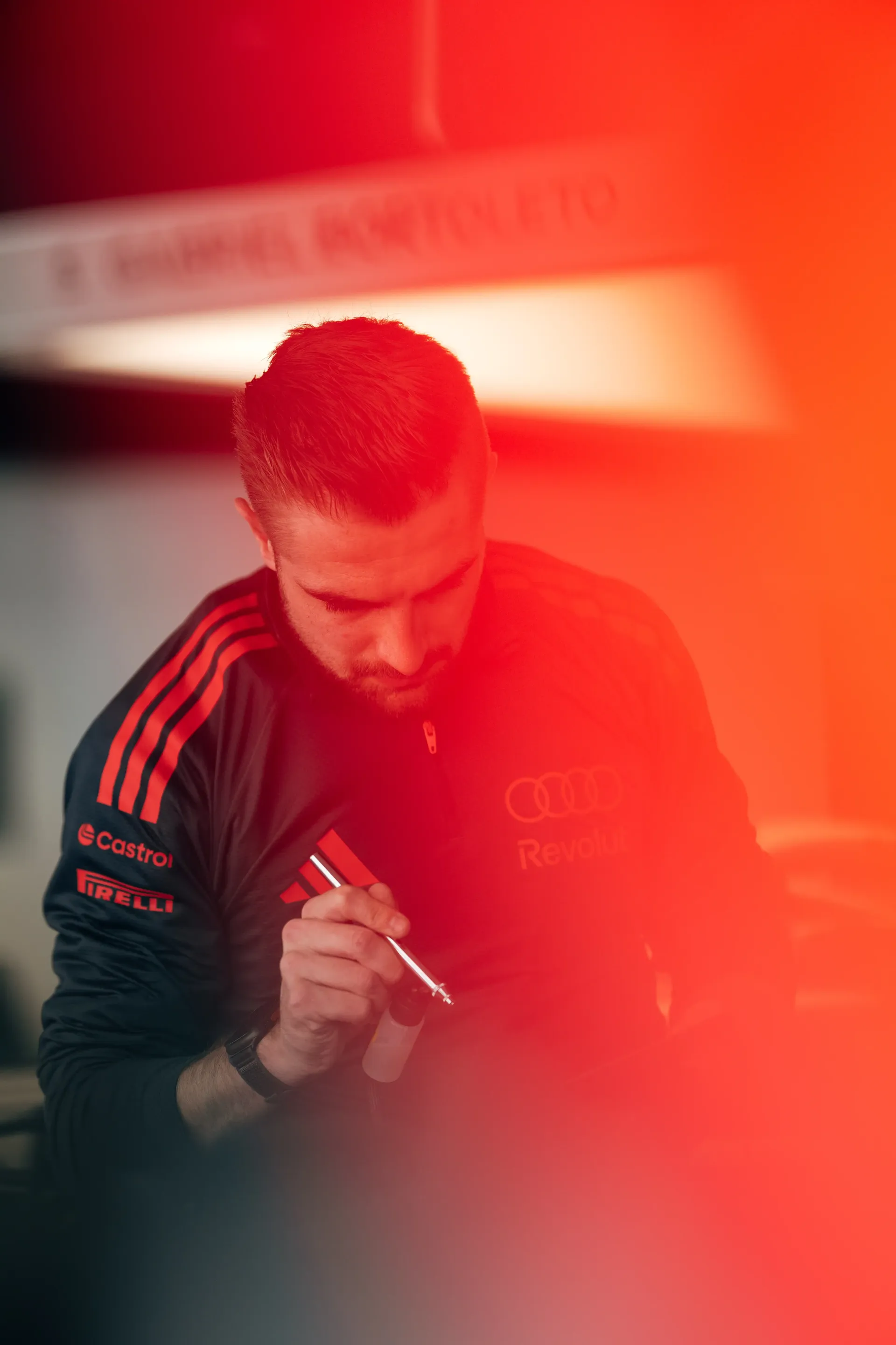 Audi Revolut F1® Team mecahnic illuminated by dramatic red lighting during Suzuka media day, showcasing focus and intensity ahead of the Japanese Grand Prix F1® race weekend.