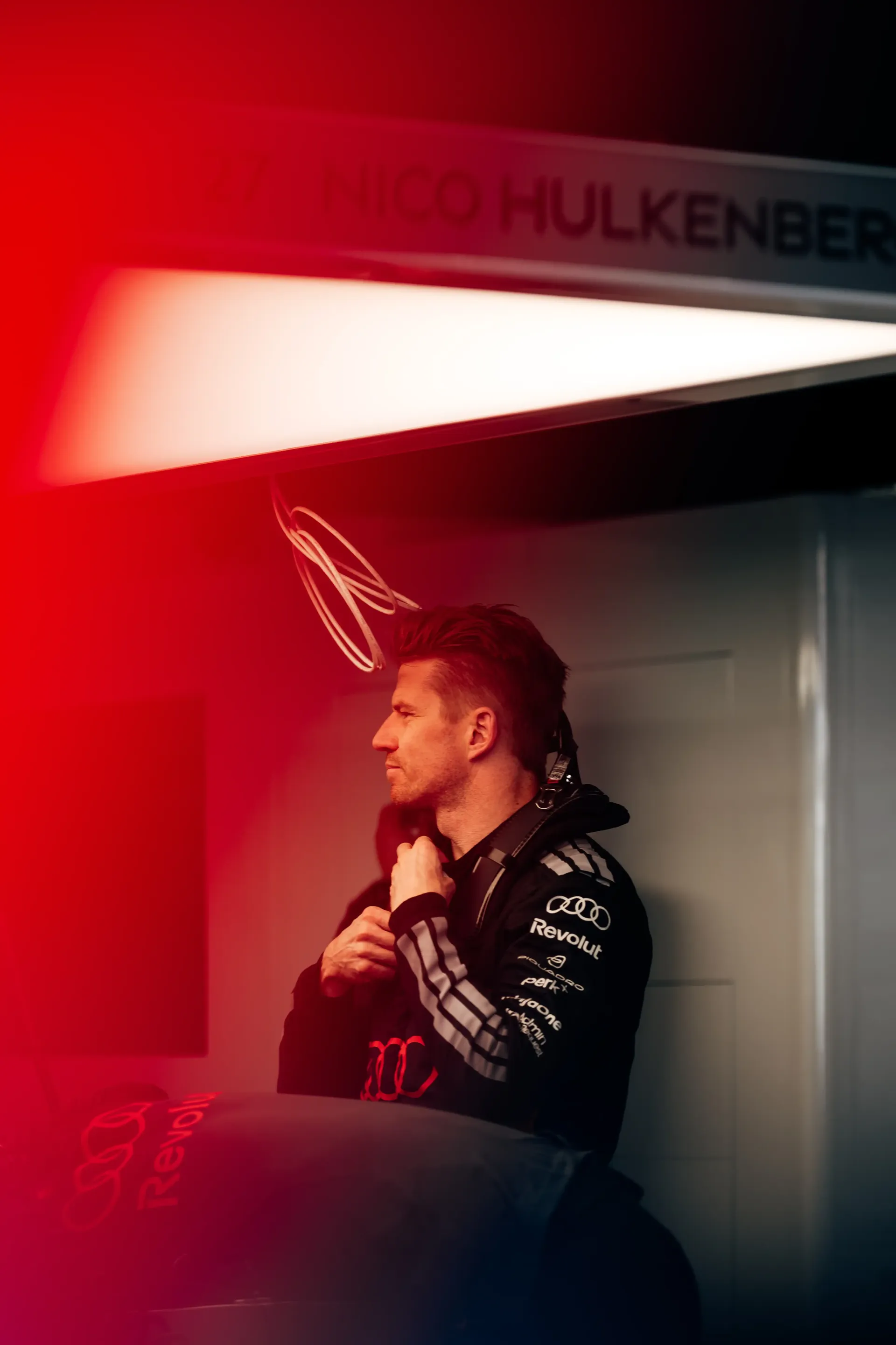 Dynamic portrait of Audi F1® driver Nico Hulkenberg in red-lit garage environment, emphasizing intensity and focus during Suzuka media day ahead of F1® race weekend