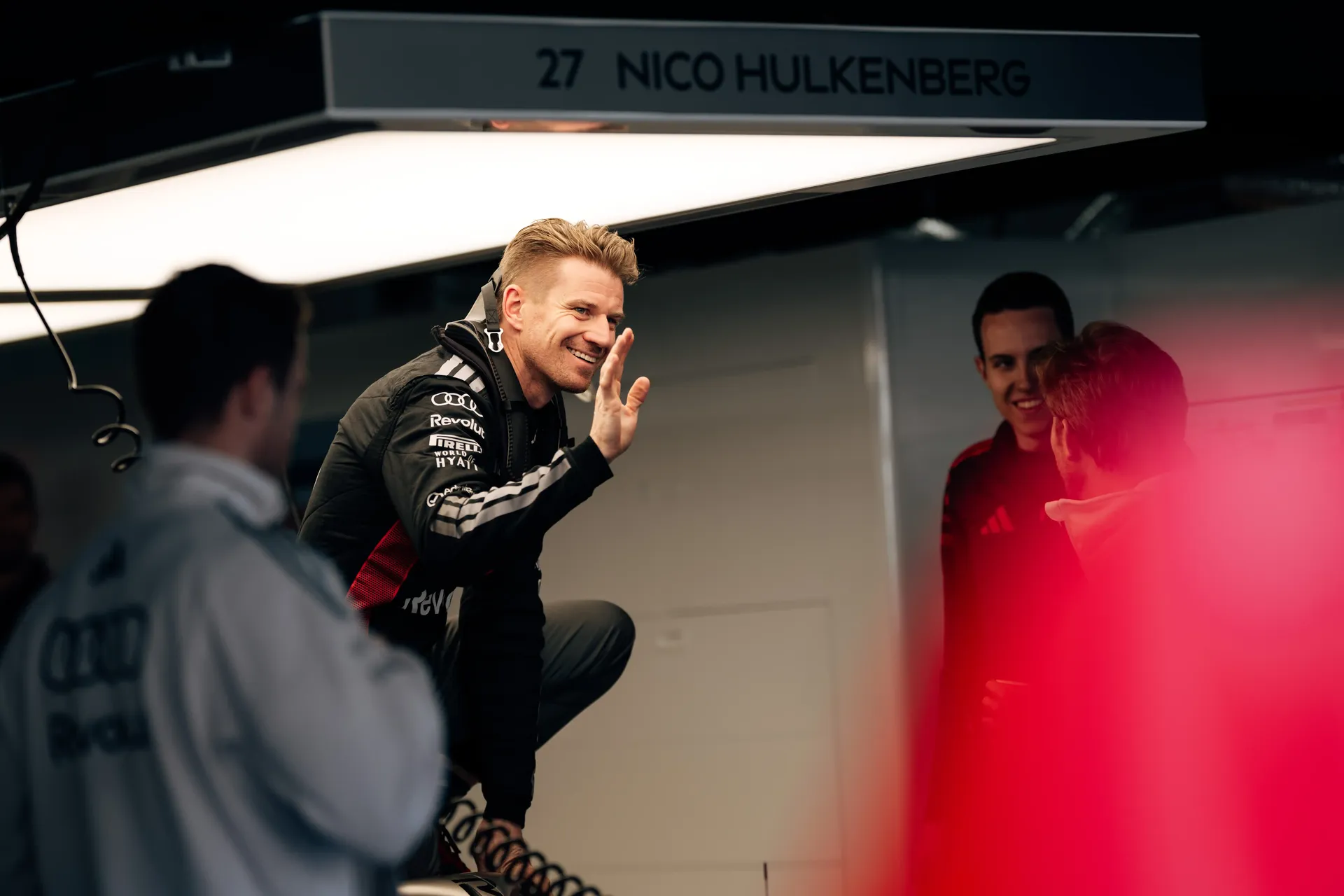 Nico Hülkenberg waves to team members inside the Audi Revolut F1® garage at Suzuka Circuit during Japanese Grand Prix F1® media day, capturing a candid moment of team interaction, positive energy, and behind-the-scenes atmosphere ahead of race weekend.