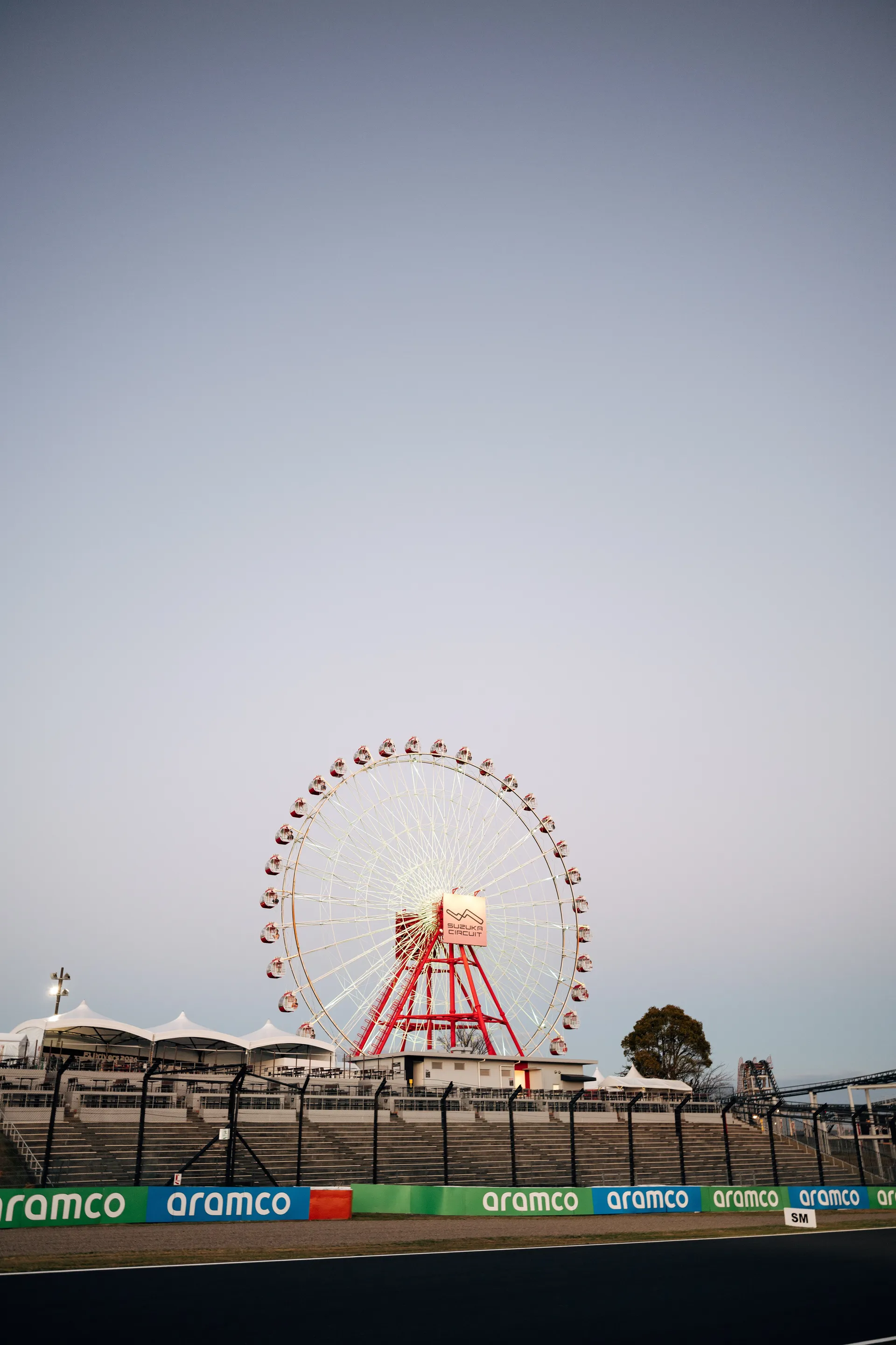 The Suzuka Ferris wheel rises above the circuit and grandstands at dusk.