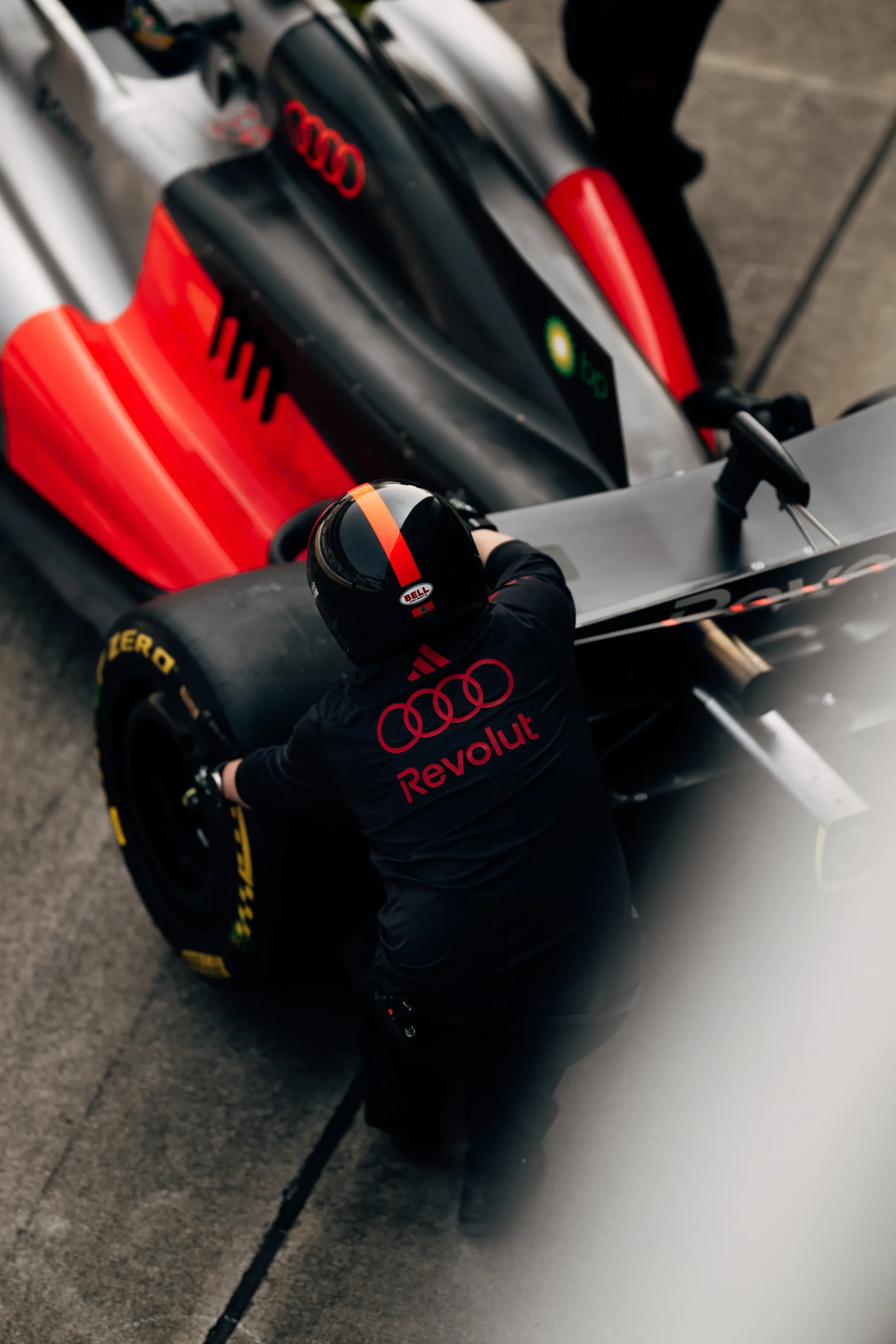 Overhead view of an Audi Revolut F1® Team crew member working beside the rear of the car in the pit lane.