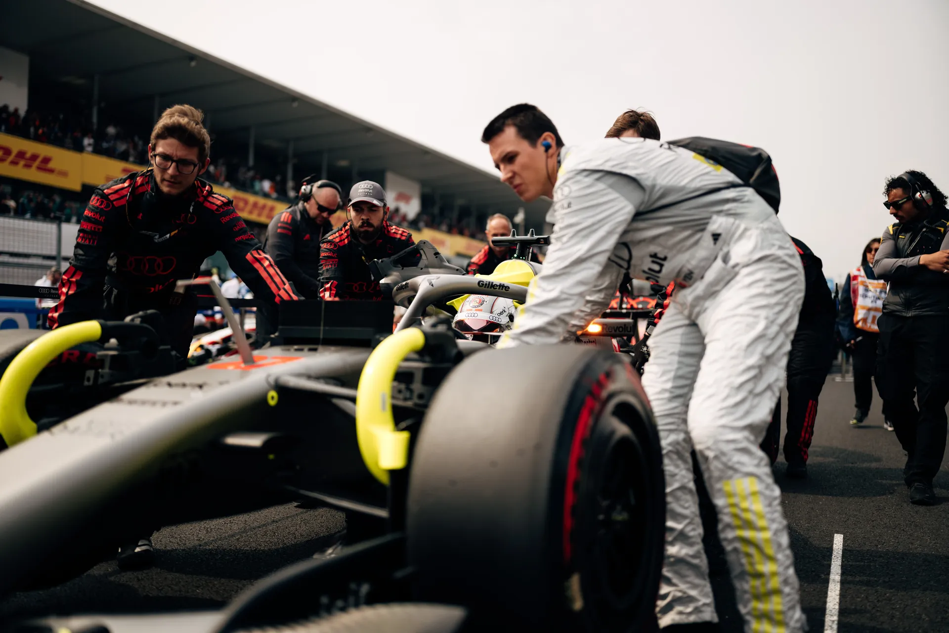 Crew members push Nico Hulkenberg’s car into position on the grid while he sits in the cockpit.
