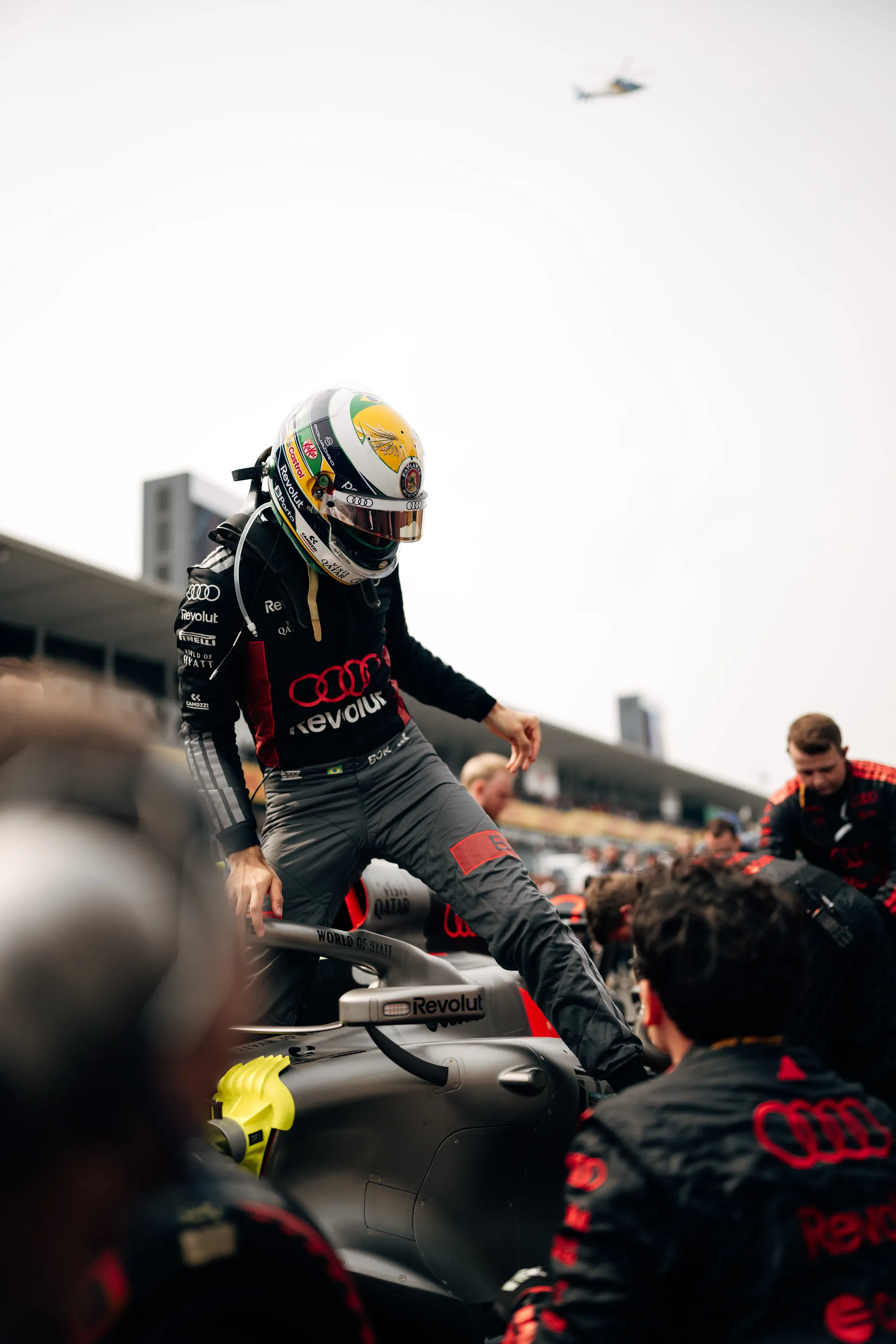 Gabriel Bortoleto climbs out of the car on the grid as Audi Revolut F1® Team crew members gather around him.