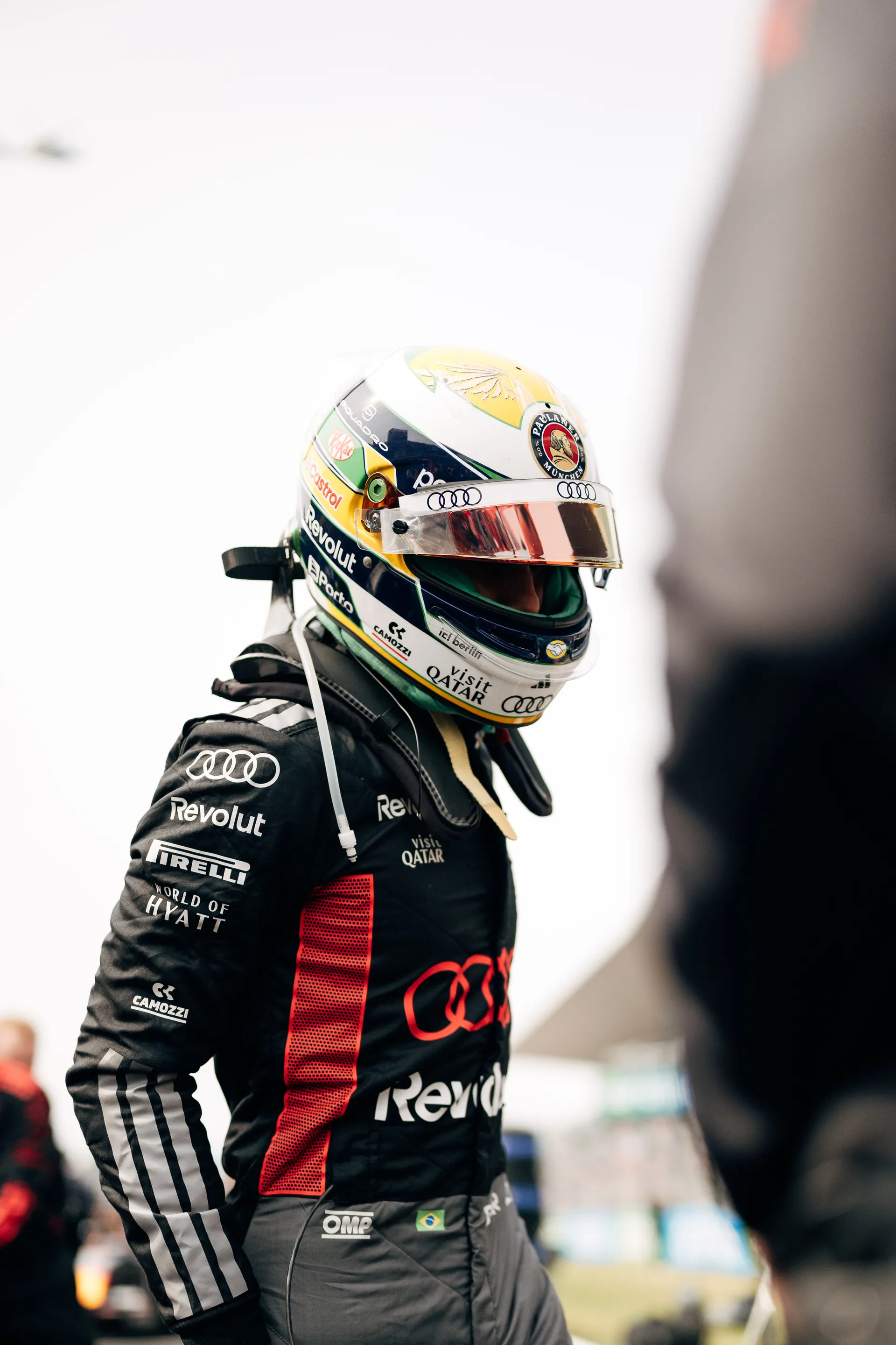 Gabriel Bortoleto stands beside the car in full race gear and helmet before the session.