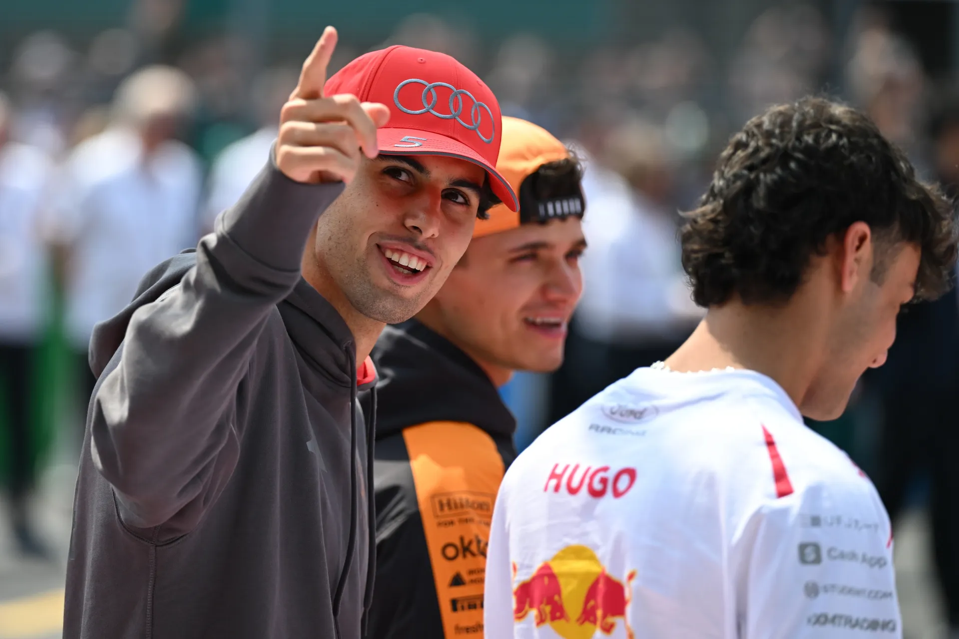 Gabriel Bortoleto of Audi Revolut F1® Team smiles and points toward the crowd while standing beside fellow drivers on the grid before the race.