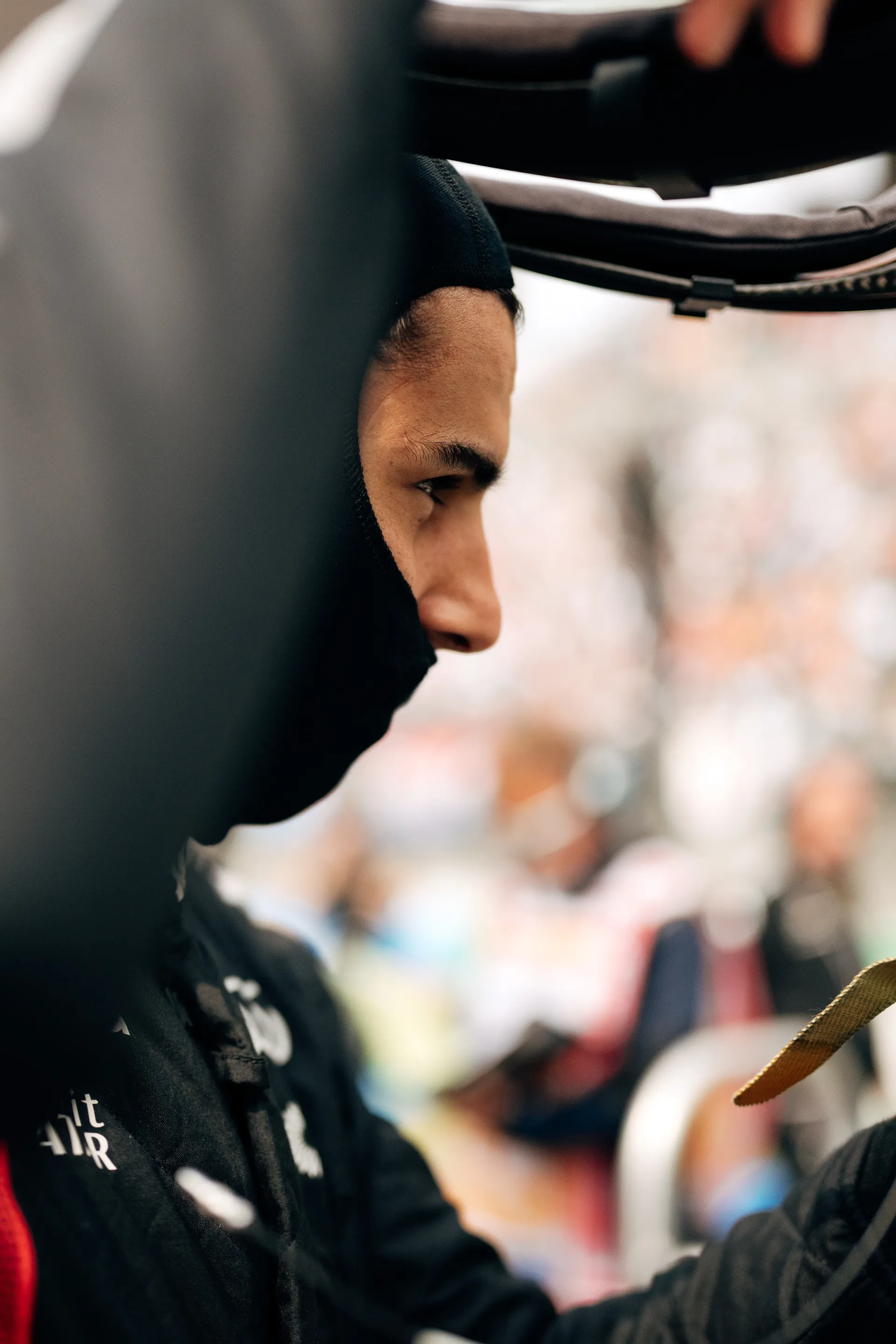Gabriel Bortoleto of Audi Revolut F1® Team is shown in close side profile wearing a black balaclava beside the cockpit before heading out.