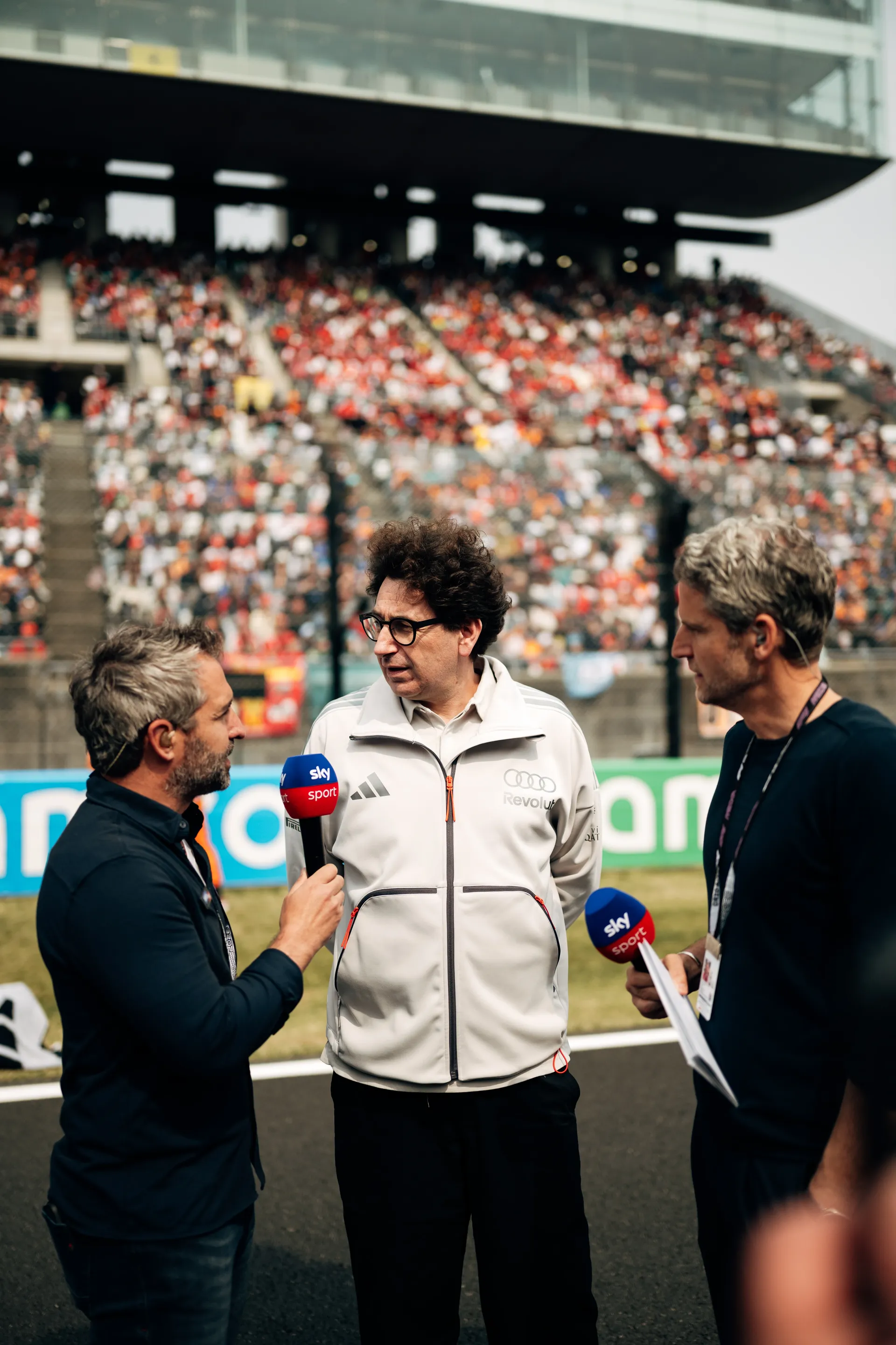 Mattia Binotto of Audi Revolut F1® Team speaks with two Sky Sport presenters on the Suzuka grid, holding position in front of the grandstands during a pre race interview.
