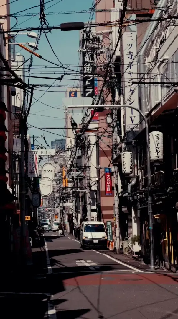 Empty narrow street in a Japanese city with shops and power lines, early morning atmosphere near Suzuka during race weekend.