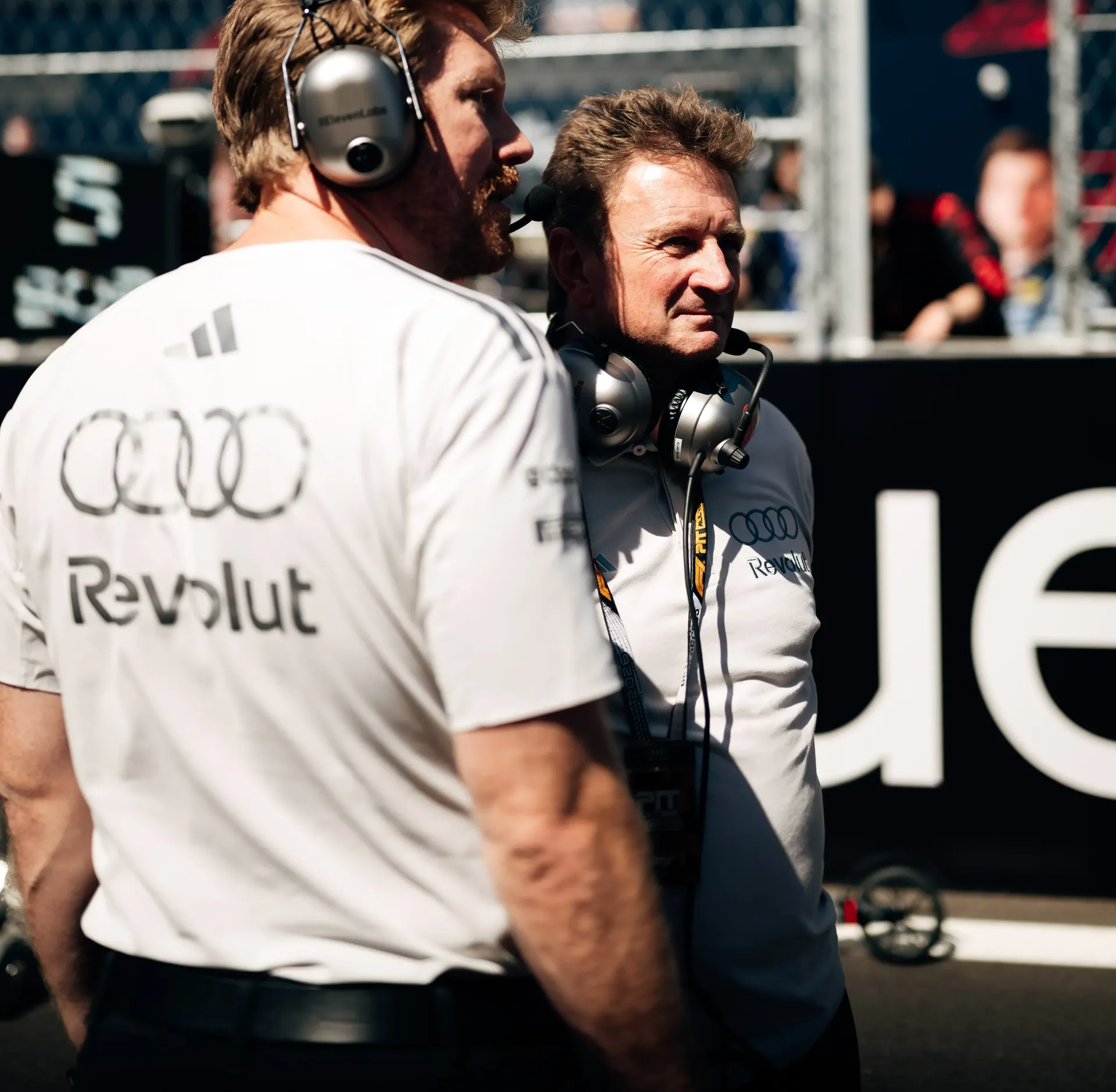 Two team members of the Audi Revolut F1® Team with headsets on the grid in Madrid