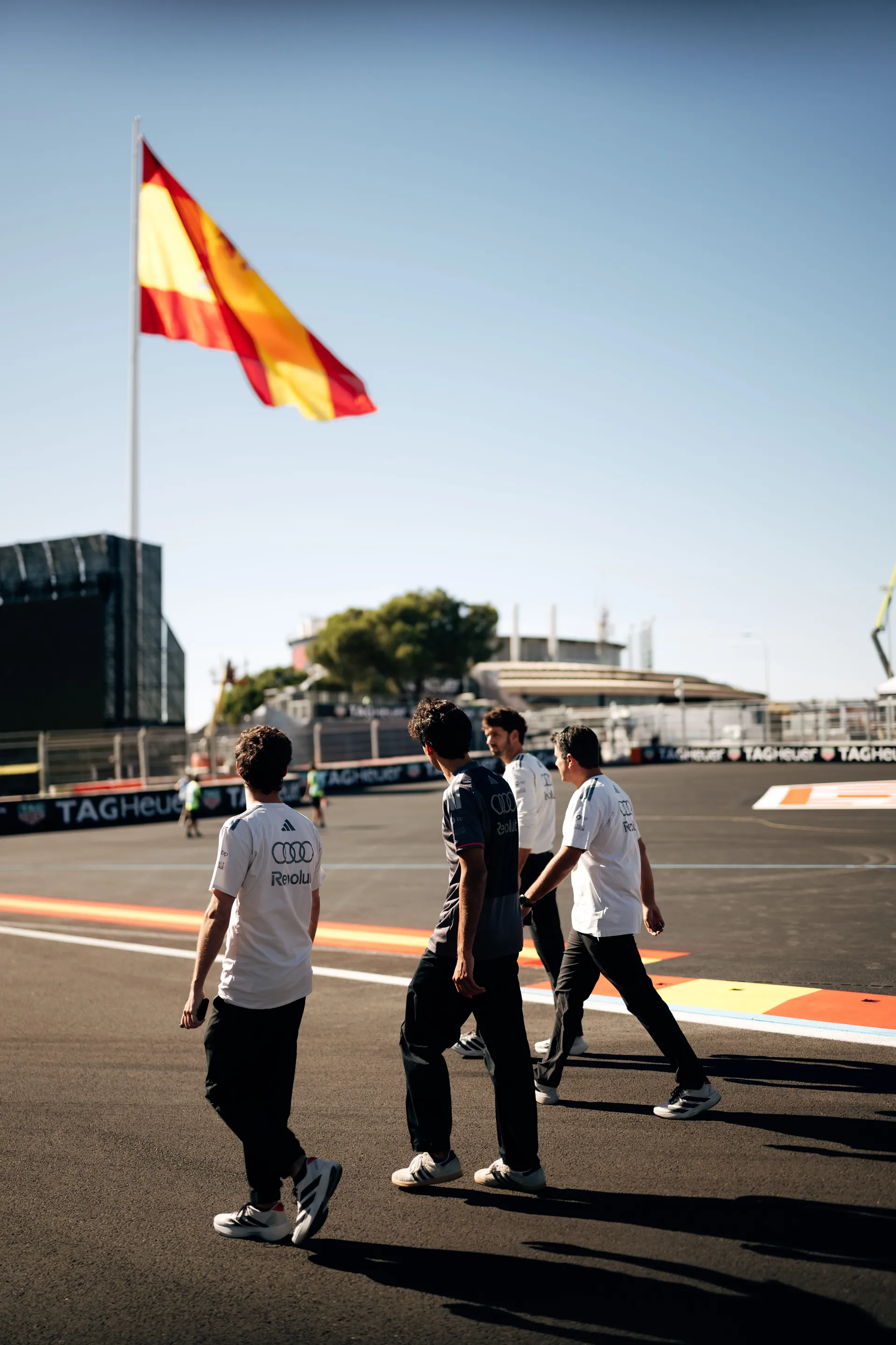 Audi Revolut F1® Team drivers and staff walking the Madring track beneath a Spanish flag