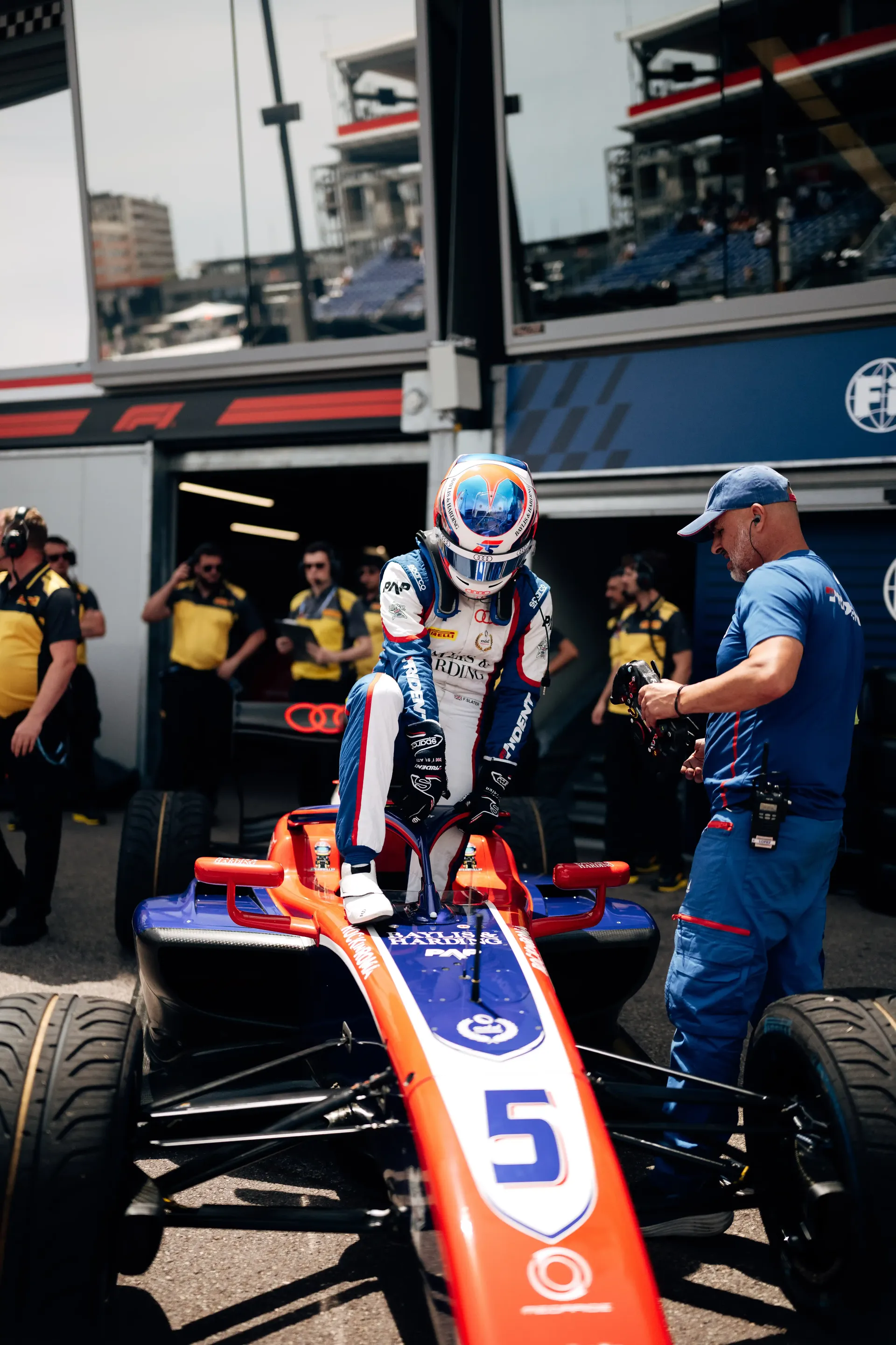Freddie Slater sits in his number 5 FIA Formula 3 car in the Monaco paddock while team members make final preparations before heading to the track.