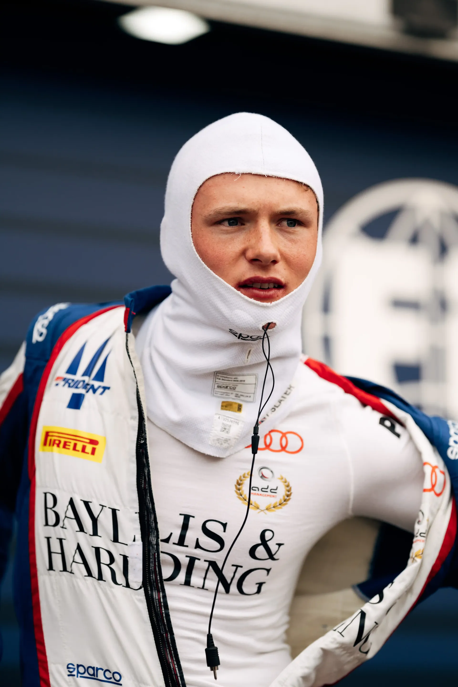 Portrait of Freddie Slater wearing a white balaclava and race suit in the Monaco paddock before getting into his Formula 3 car.