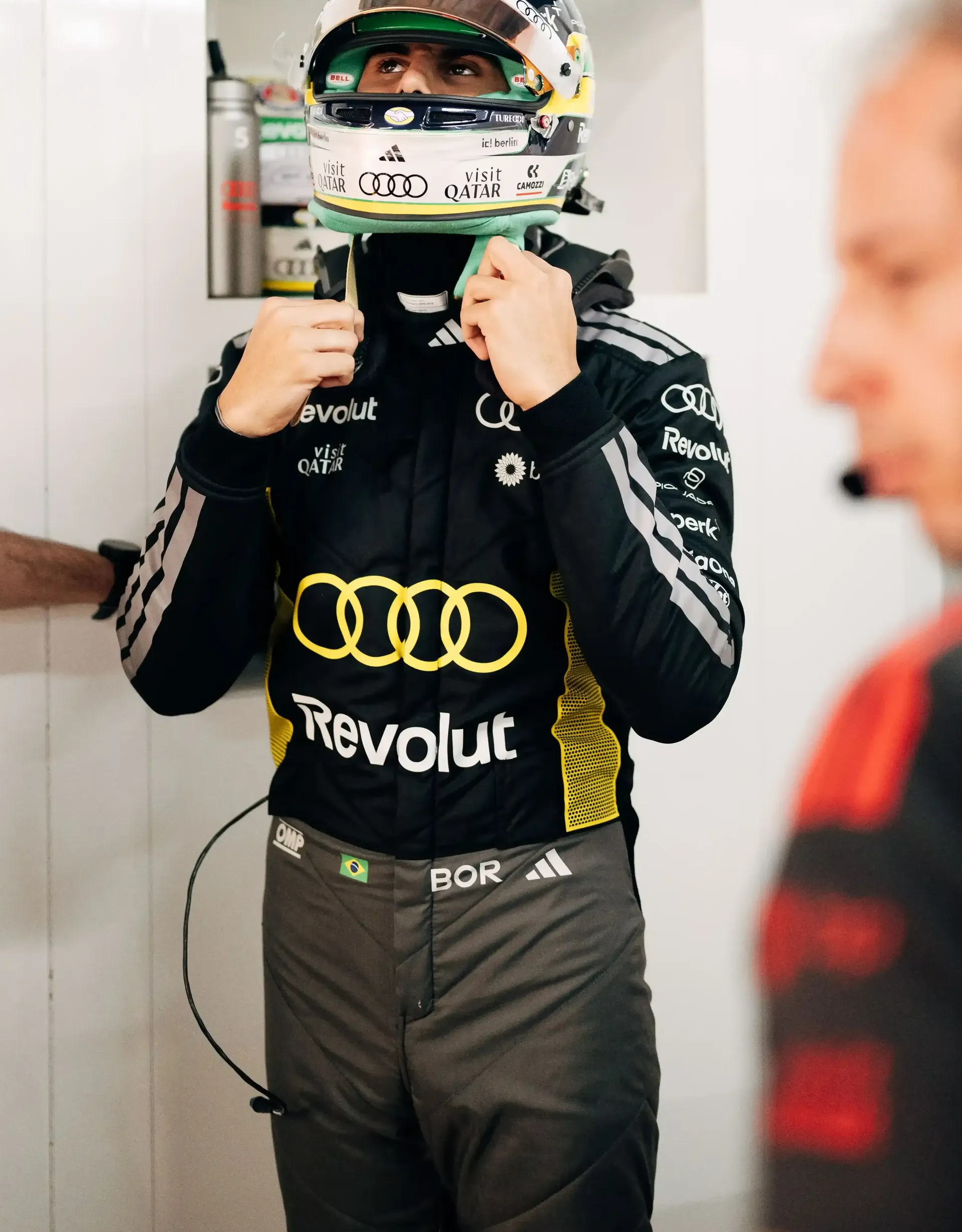 Gabriel Bortoleto driver at Audi Revolut F1® Team in full race suit and helmet stands in the garage during Monaco FP1 preparations.