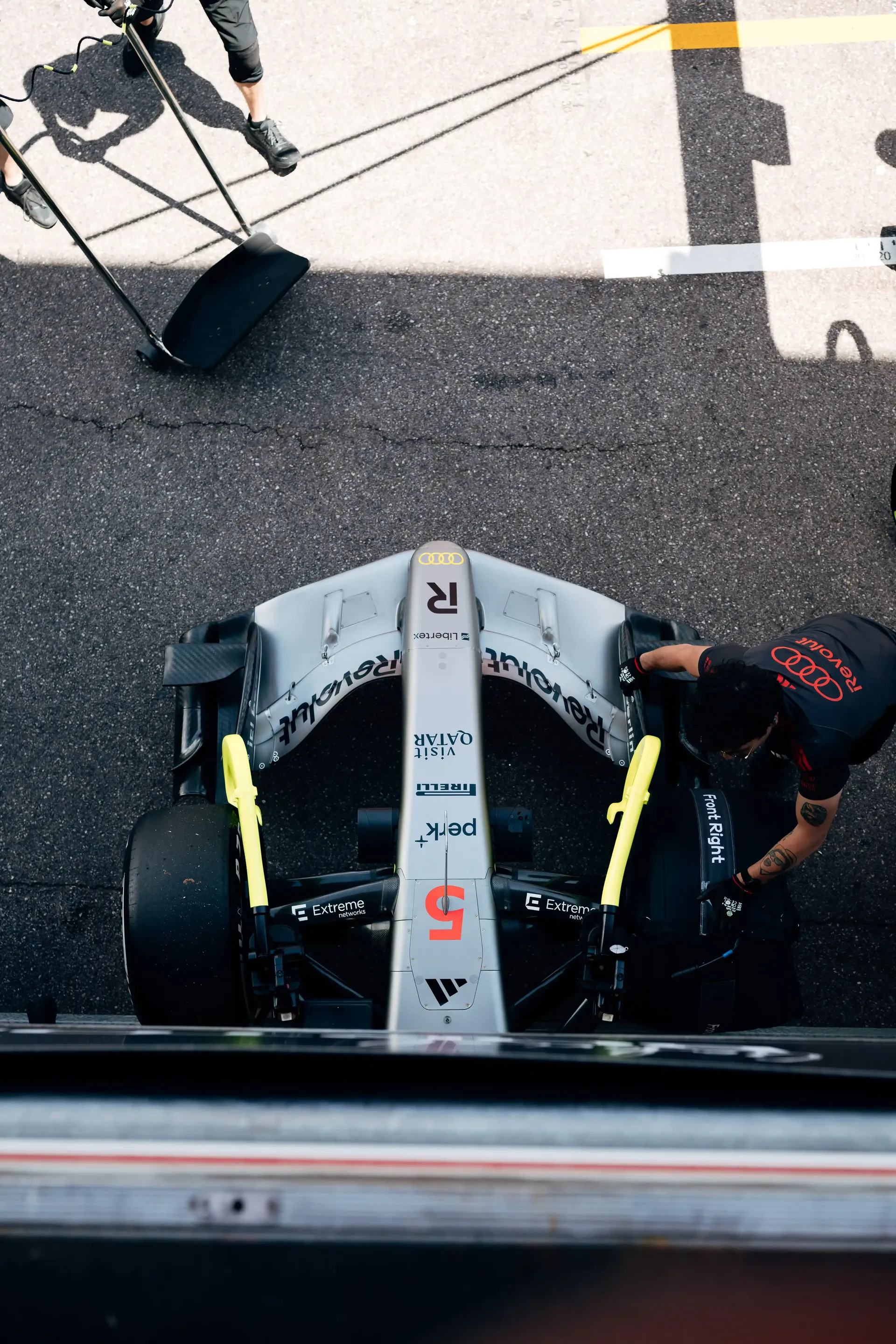 Top-down shot of the Audi Revolut F1® Team F1® car positioned in the Monaco pit box with crew members nearby.