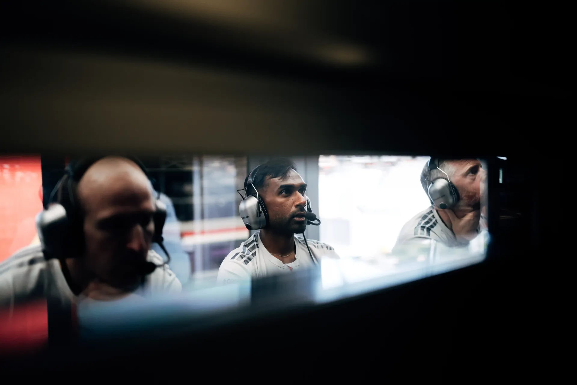 Audi Revolut F1® Team engineers wearing headsets monitor track activity from the pit wall.
