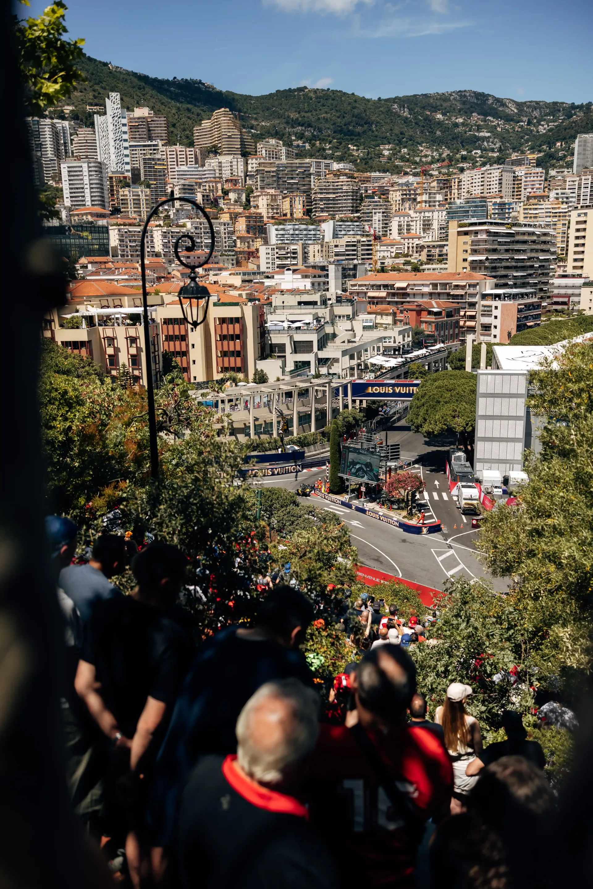 Elevated view of Monaco city streets and the circuit with spectators gathered on the hillside.