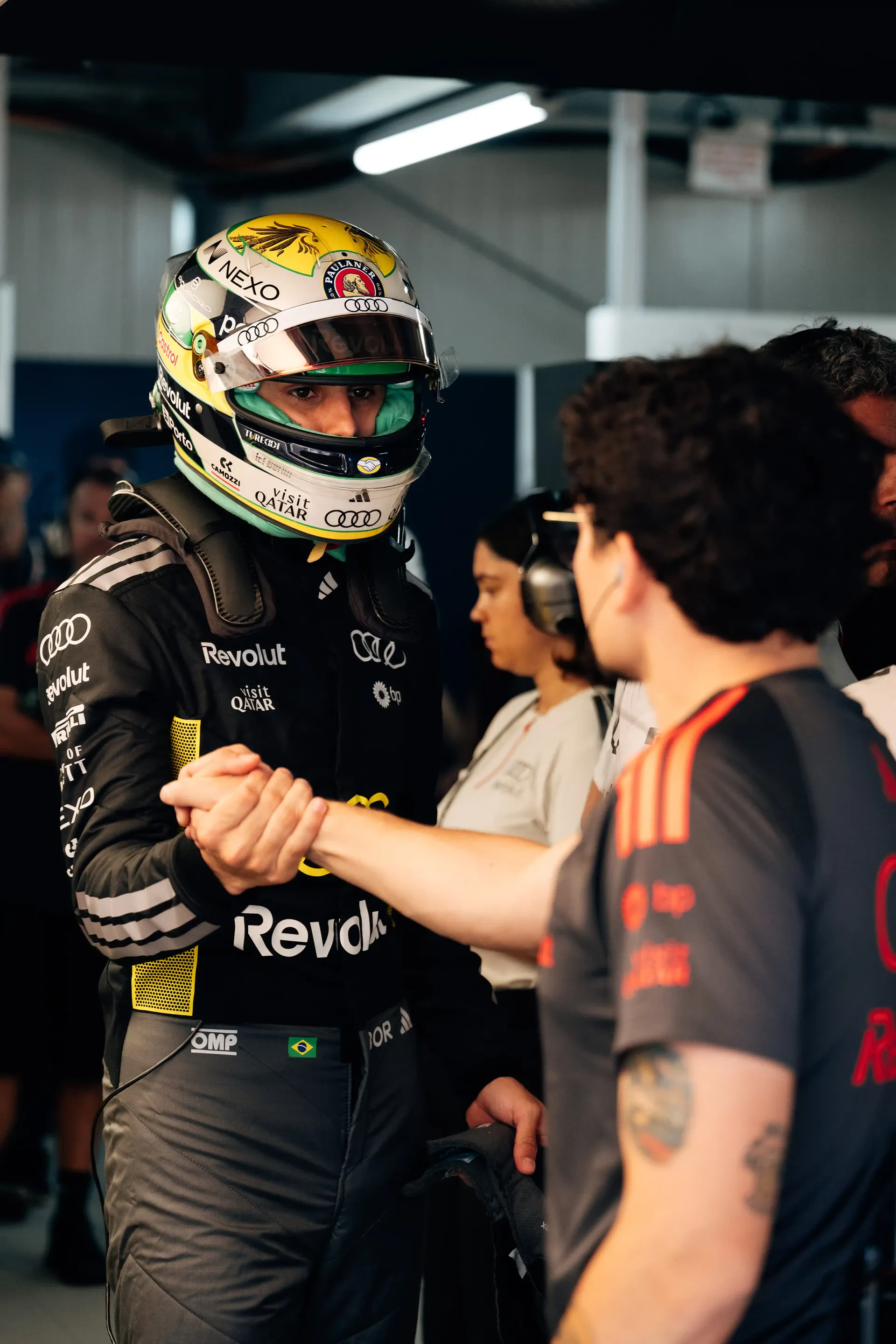 Gabriel Bortoleto in his race helmet speaks with Audi Revolut F1® Team mechanic inside the garage.