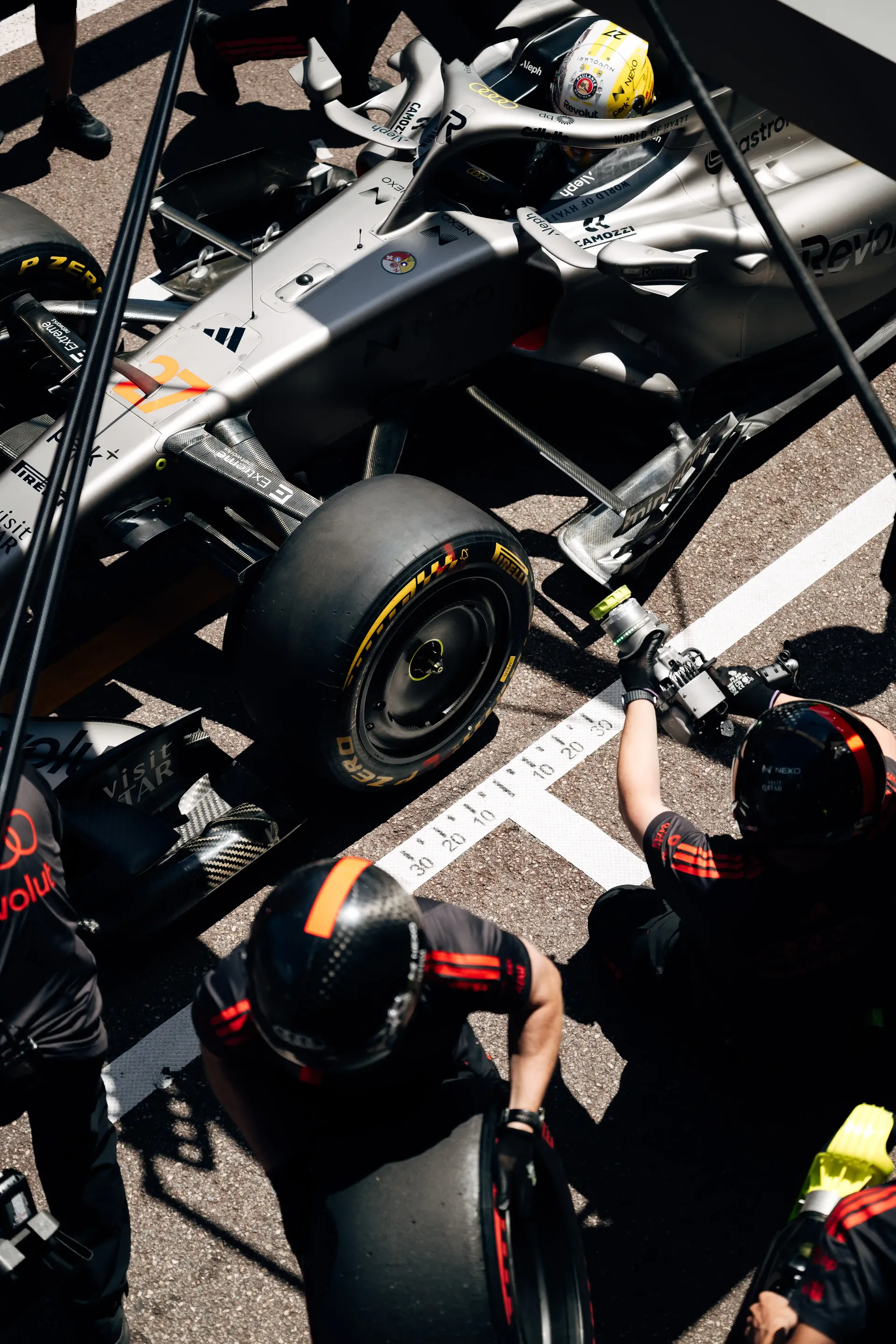 Overhead view of an Audi Revolut F1® Team pit stop action with crew surrounding the Formula 1 car R26.