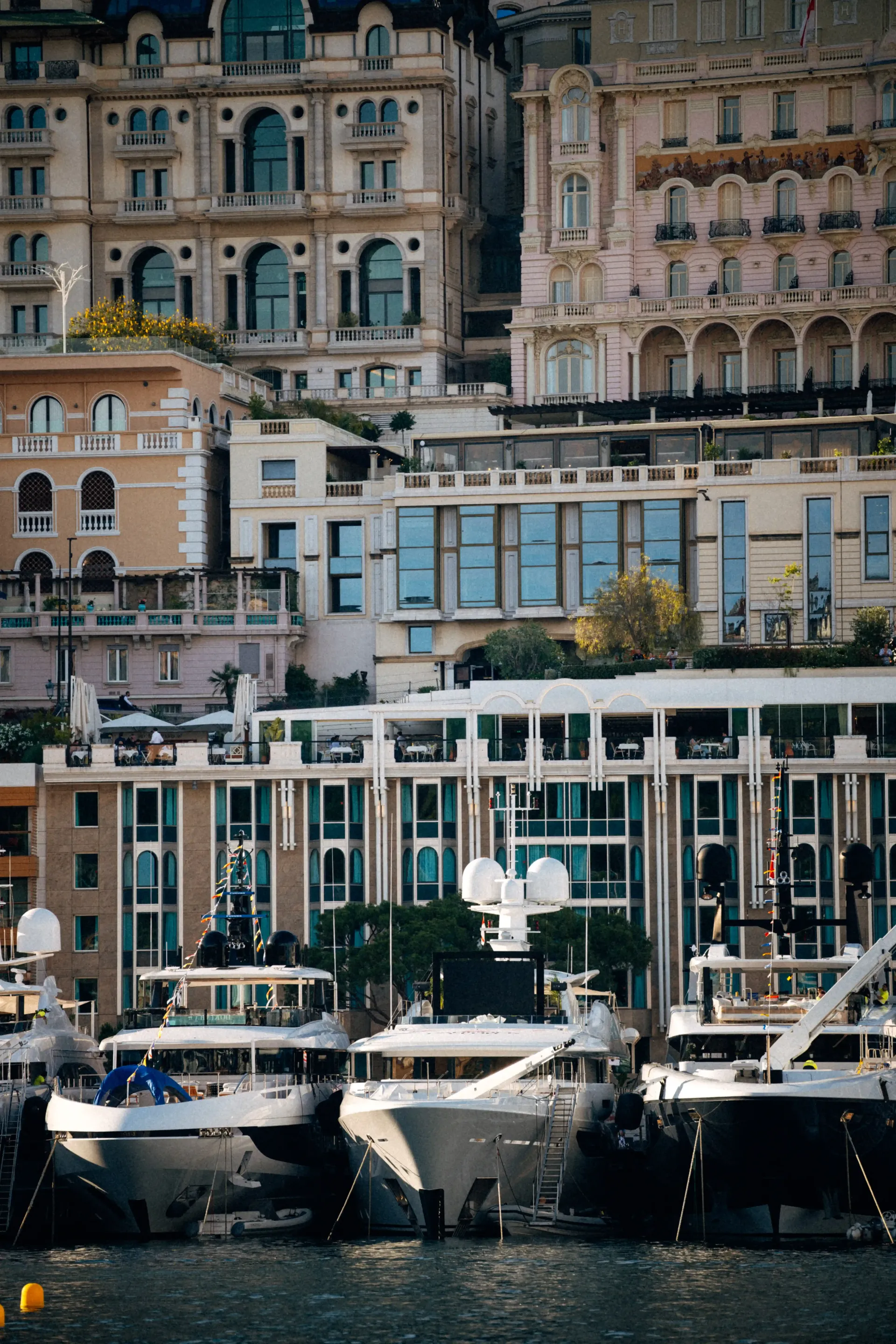 Waterfront cityscape with luxury residences overlooking moored yachts in Monaco.